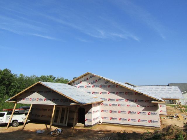 A white truck is parked in front of a house under construction.