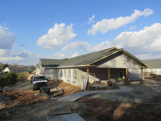 A white truck is parked in front of a house under construction