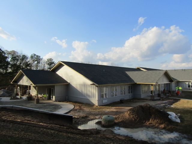 A large white house with a gray roof is under construction