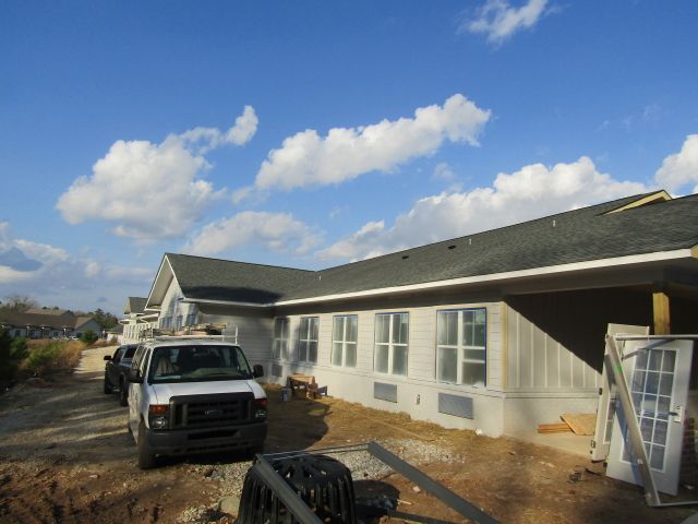 A white van is parked in front of a house under construction.