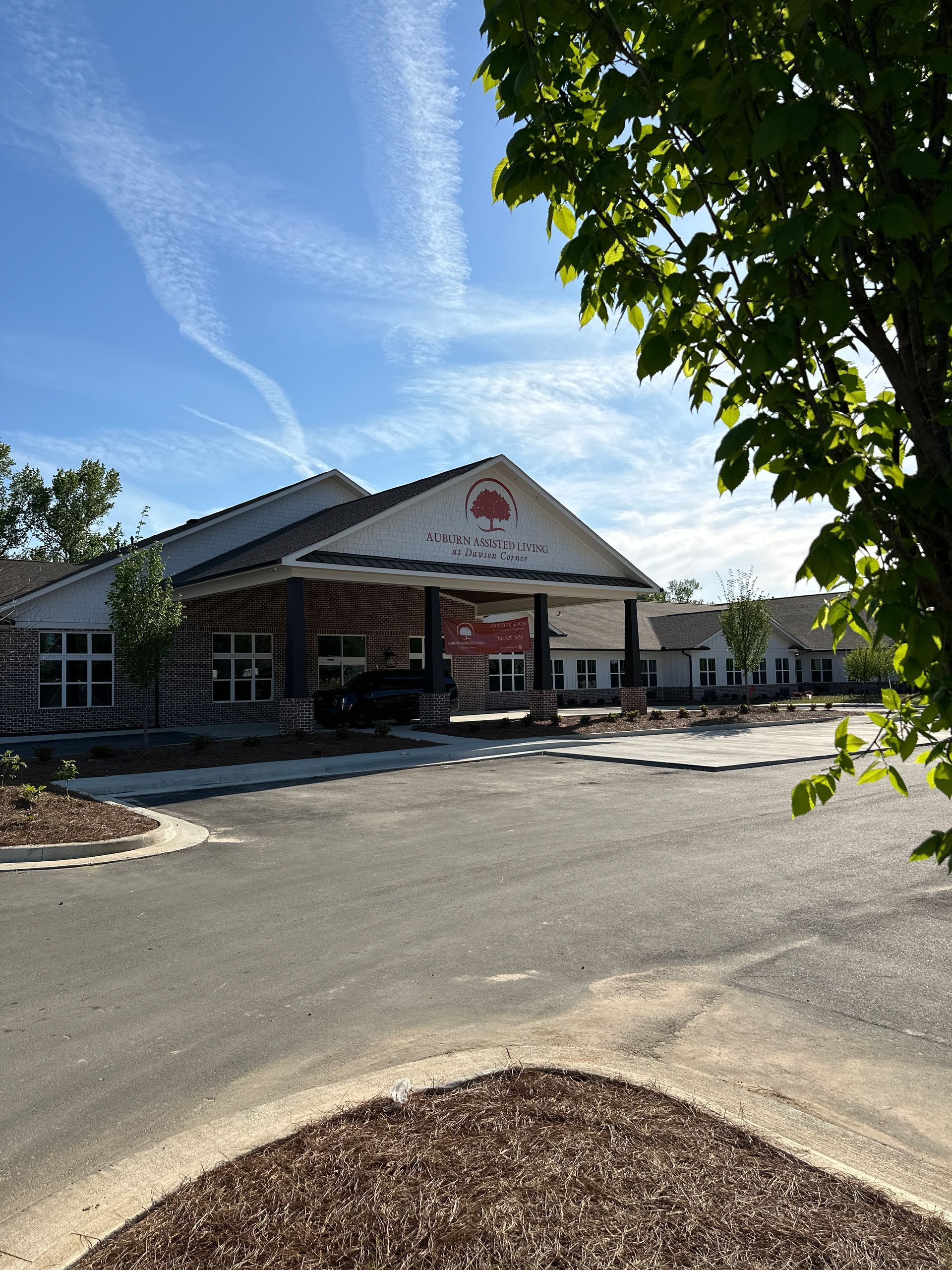 A low, modern building with a peaked entrance under a bright blue sky, viewed from an empty parking lot.