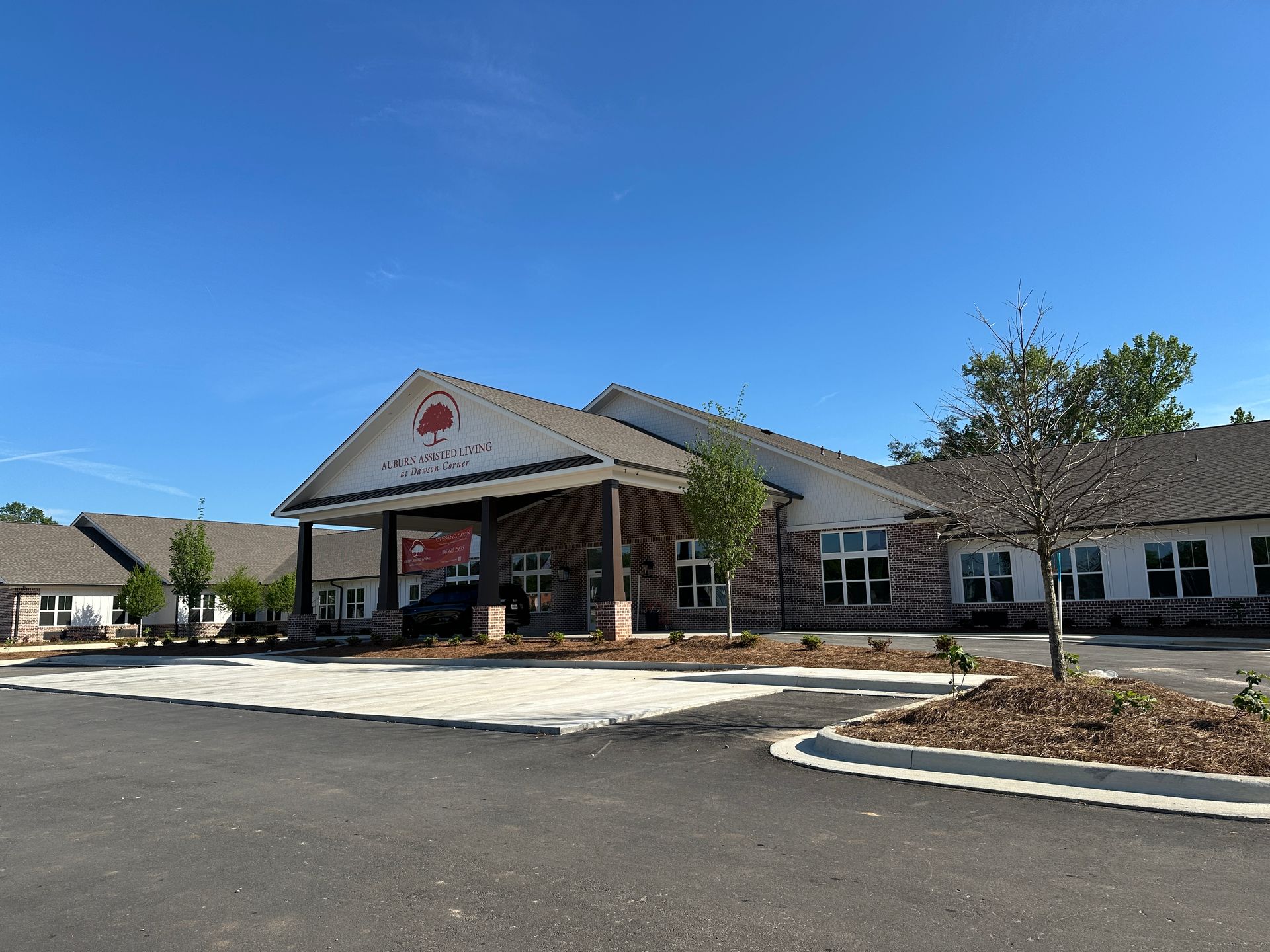 A one-story building with a red-brick exterior and a covered entryway under a clear blue sky.