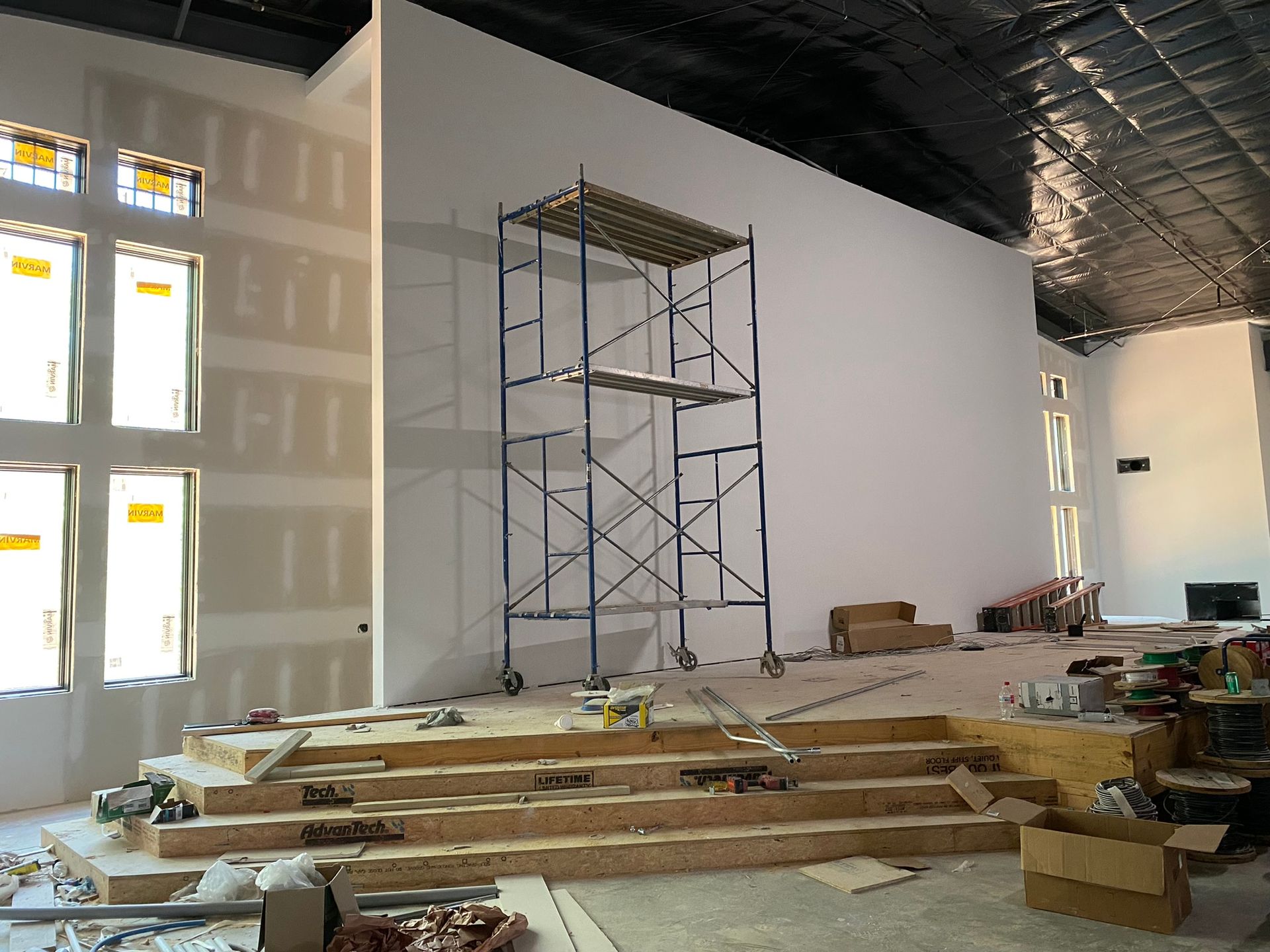 A building under construction with scaffolding and boxes on the floor.