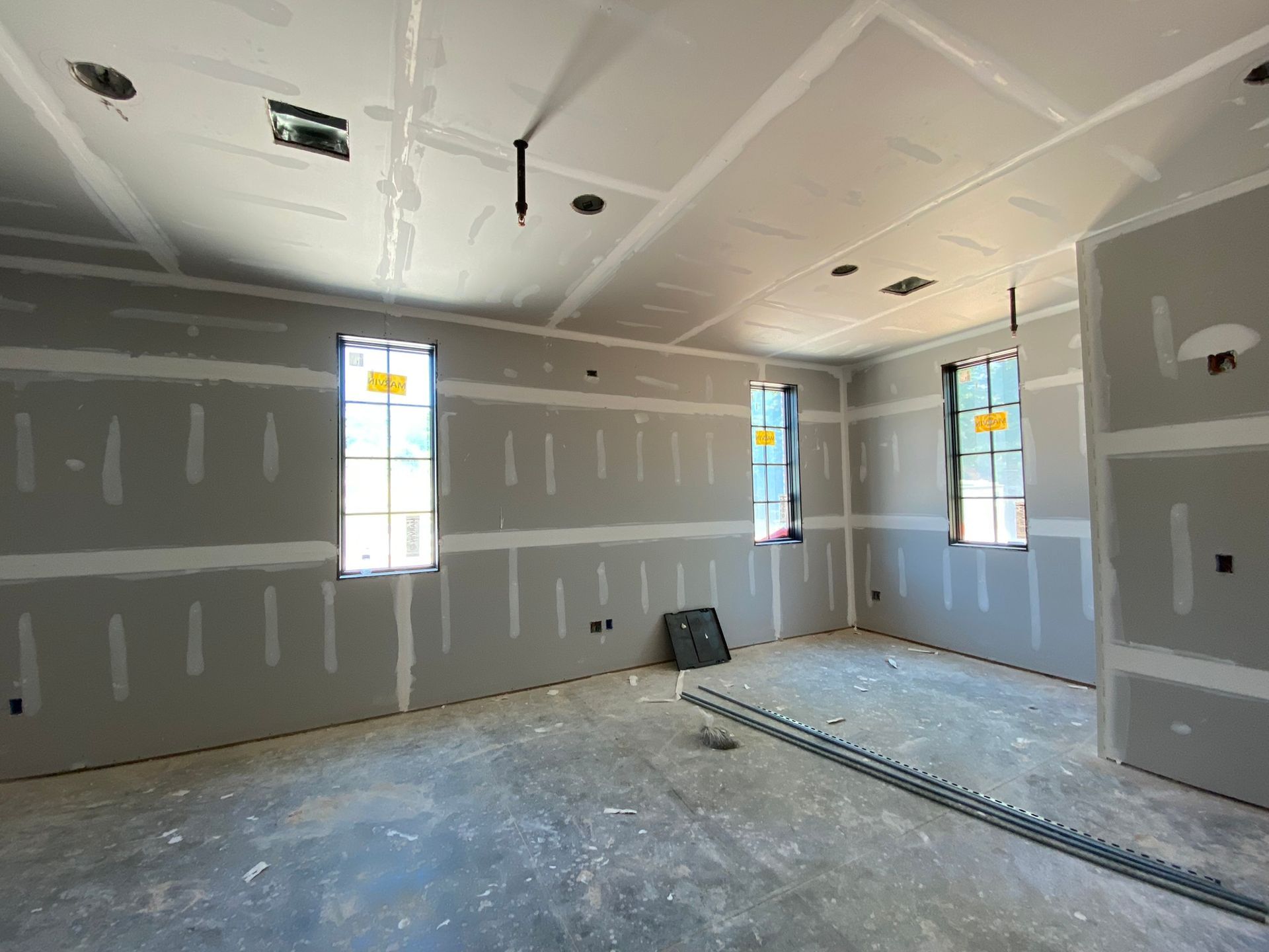 An empty room with a lot of drywall and windows.