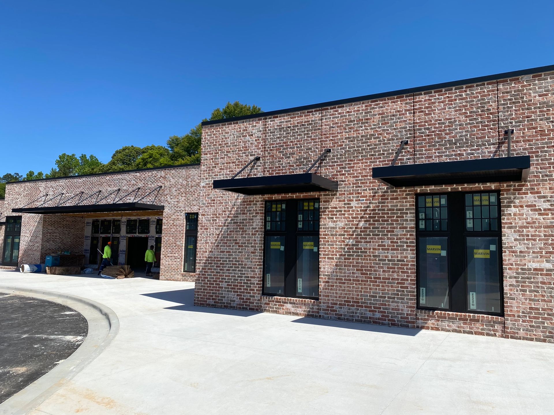 A brick building with black windows and awnings on a sunny day.