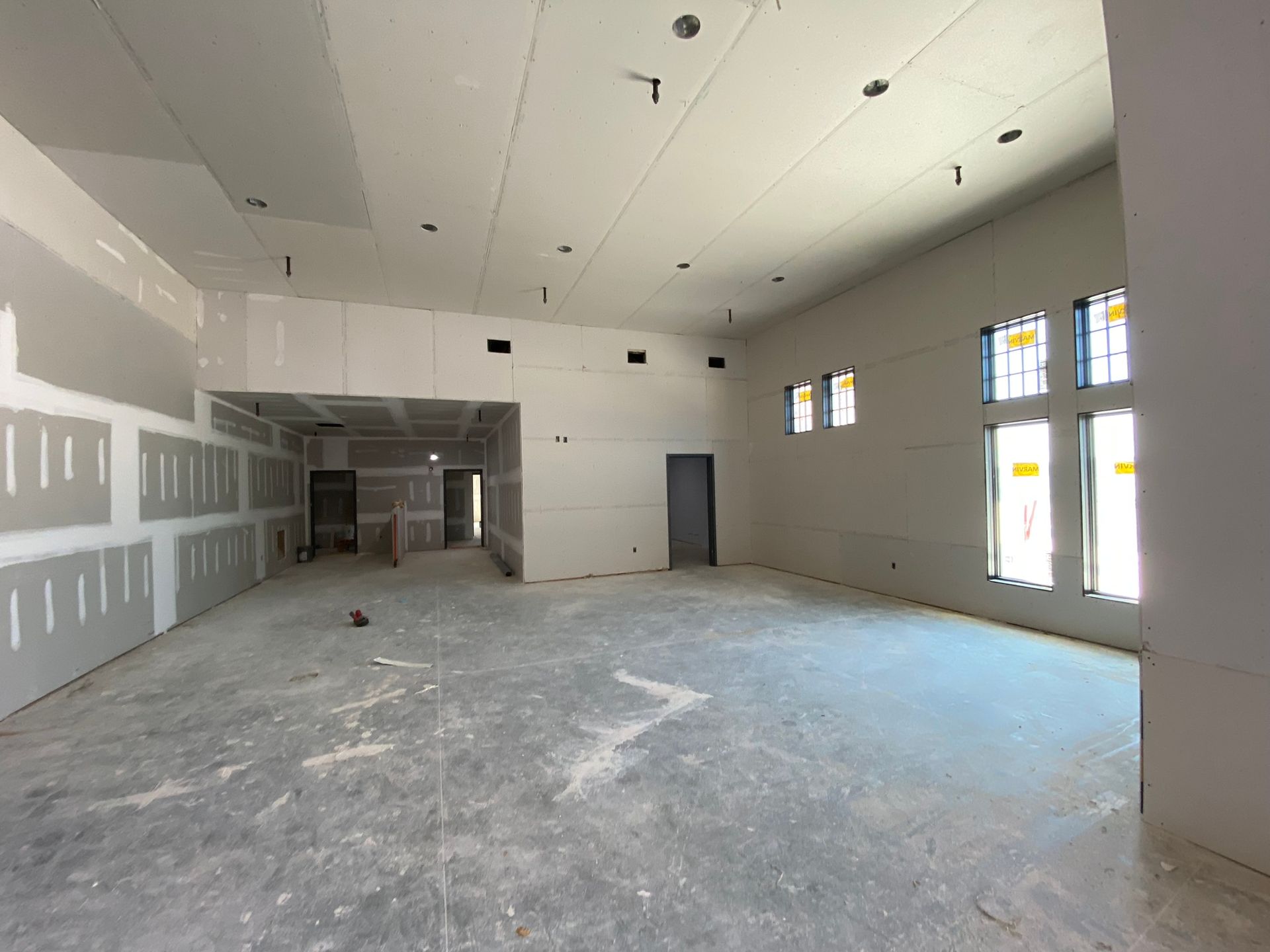 A large empty room with a lot of windows and drywall.