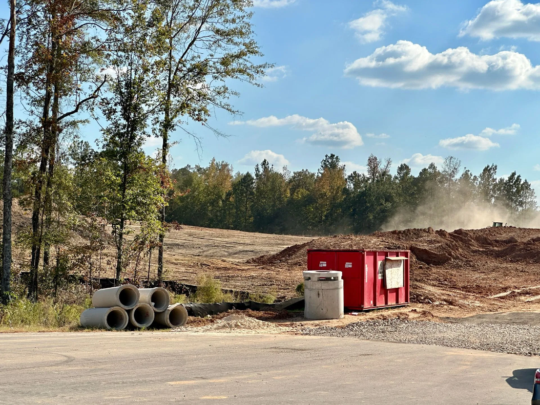 A red container sits in the middle of a dirt field