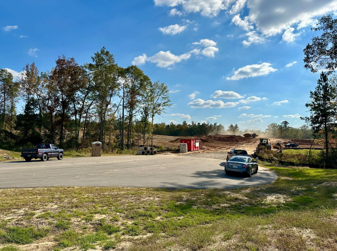 A truck is parked in a parking lot next to a construction site.