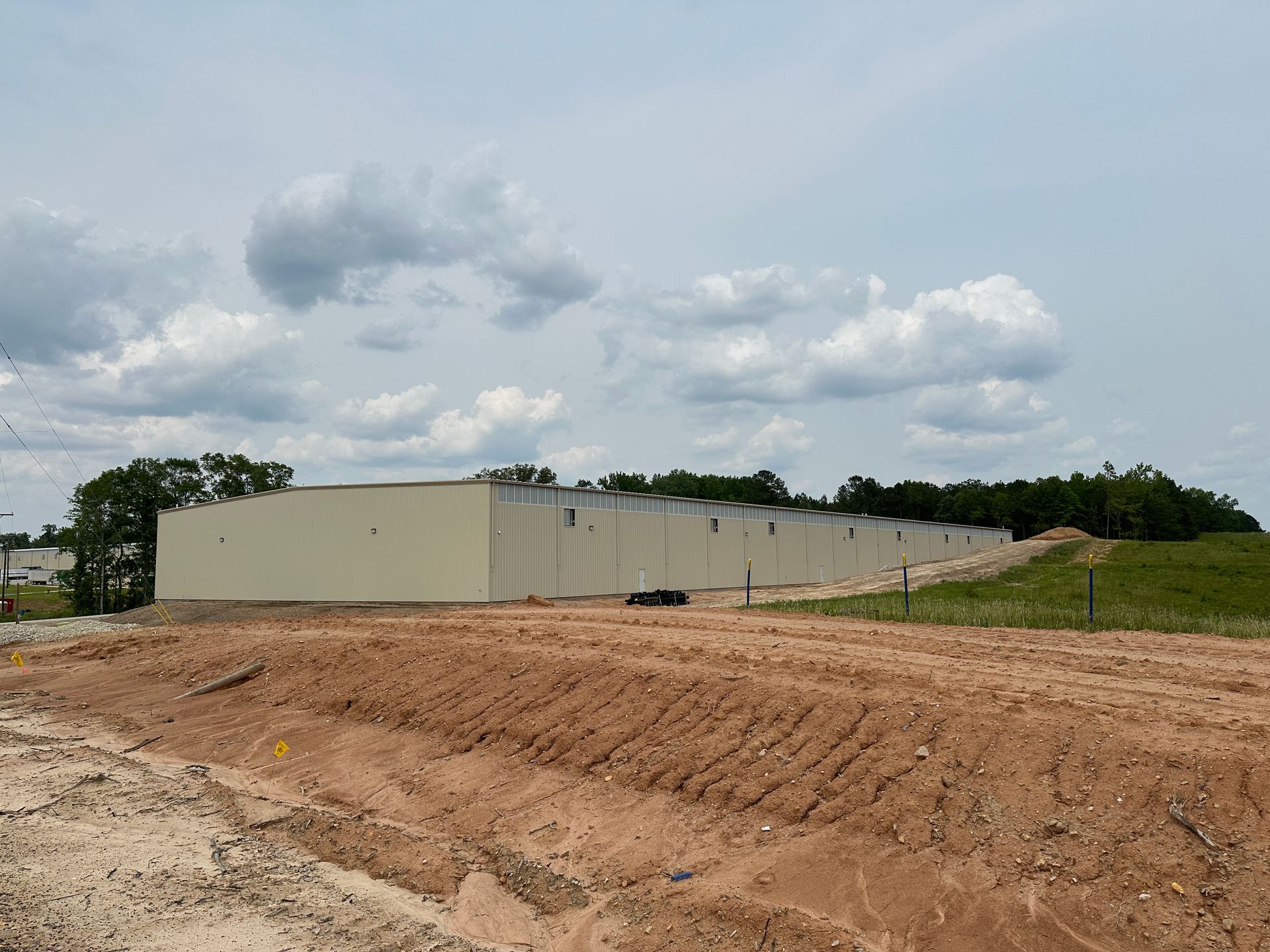 A large white building is sitting in the middle of a dirt field.