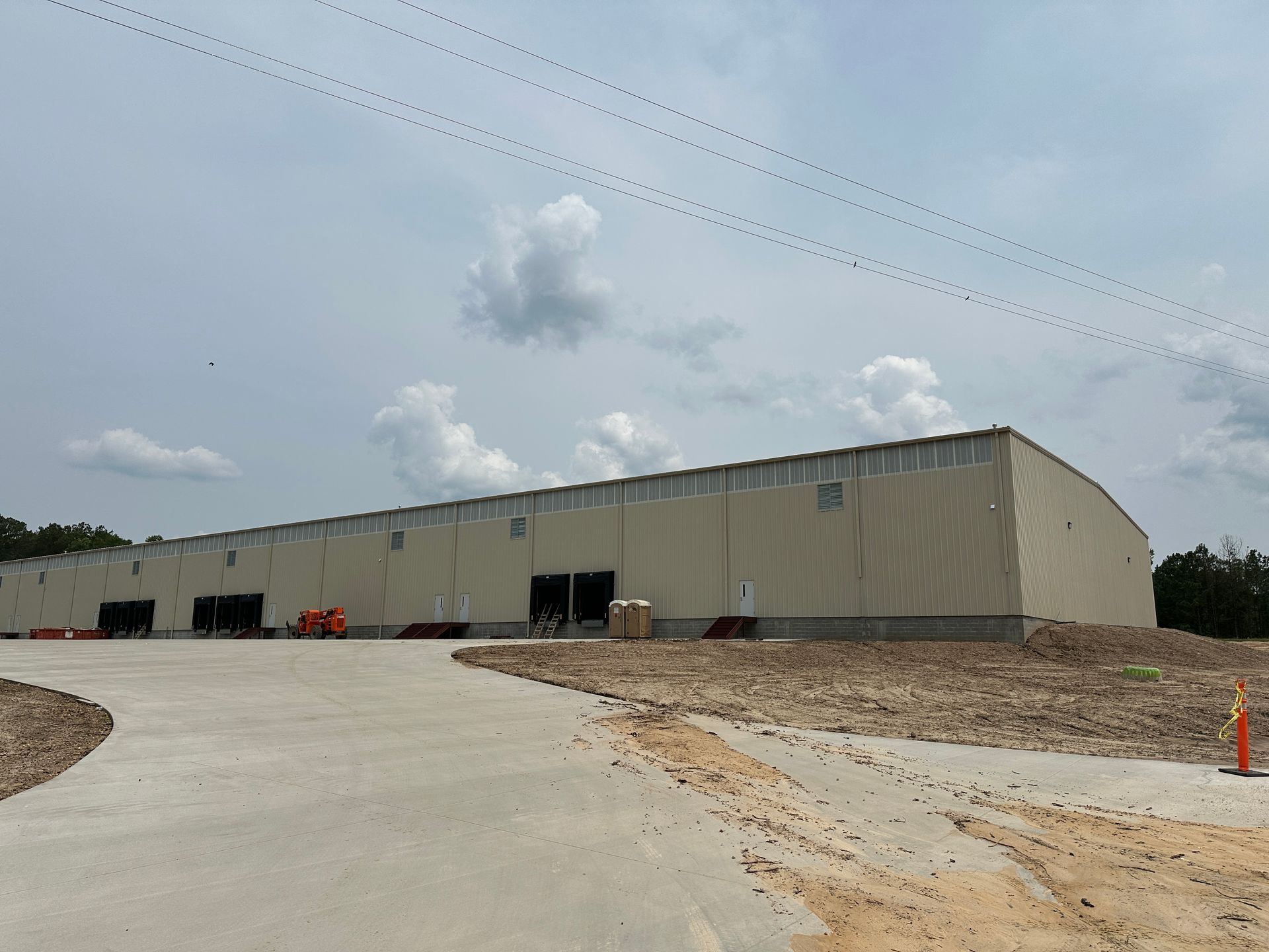 A large white building with a lot of windows is sitting on top of a dirt field.