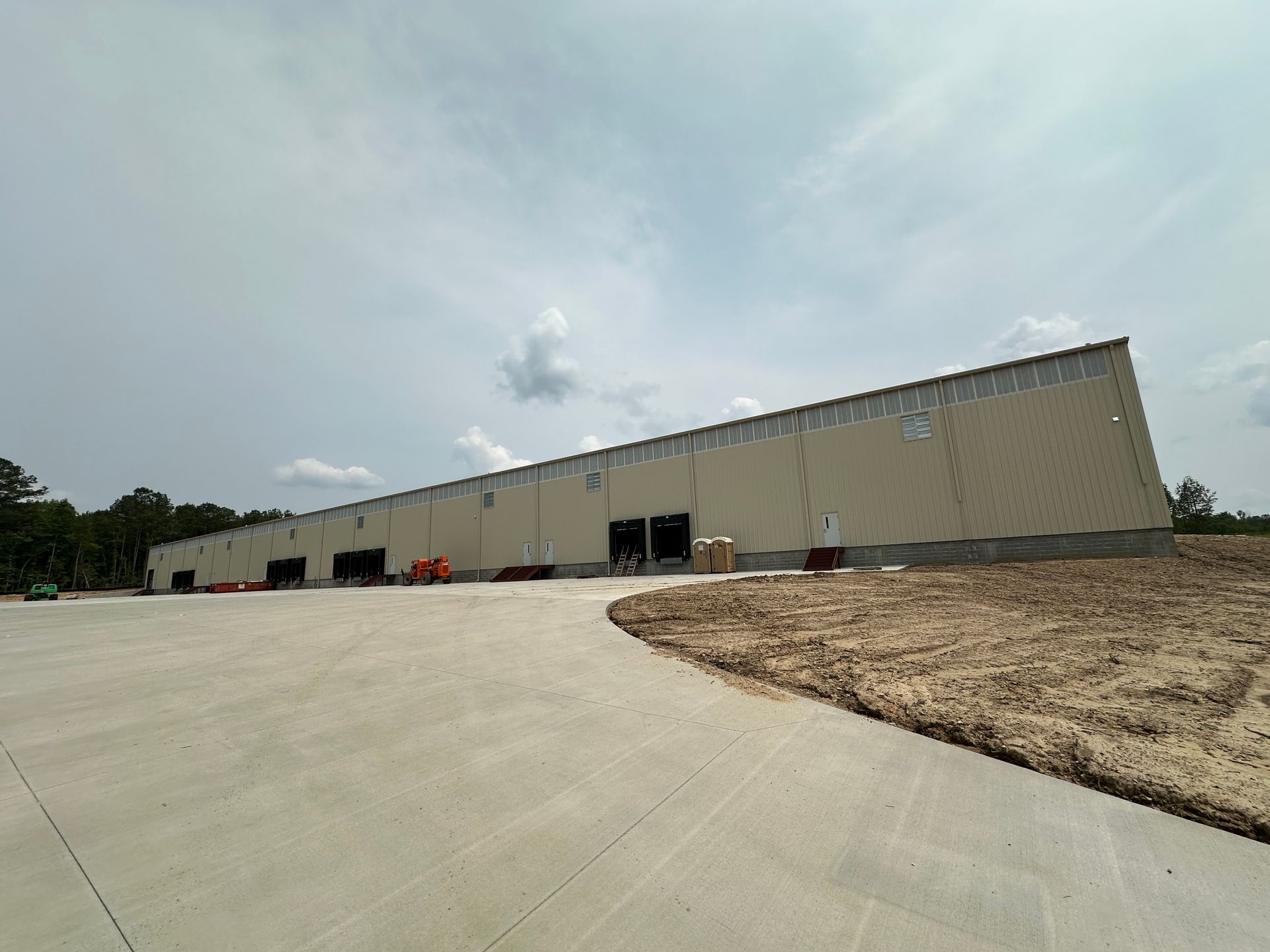 A large white building is sitting on top of a dirt field.