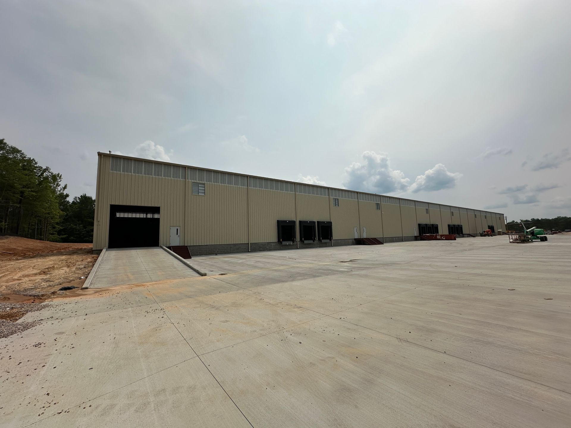 A large warehouse with a lot of doors and a concrete driveway in front of it.