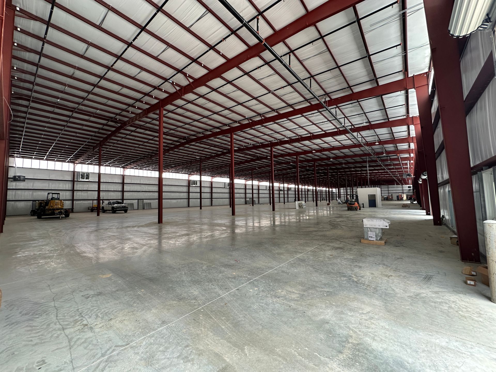 A large empty warehouse with a lot of windows and a concrete floor.