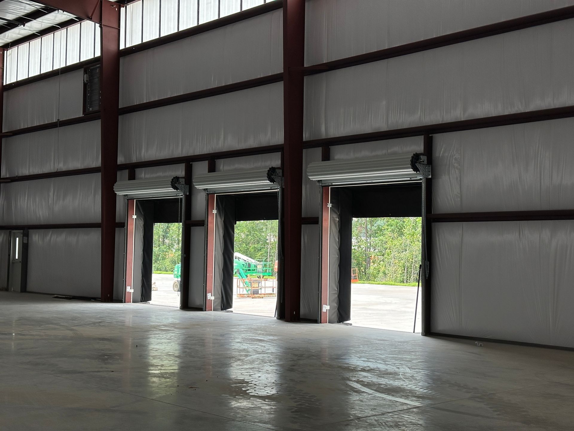 A large empty warehouse with a lot of doors open.
