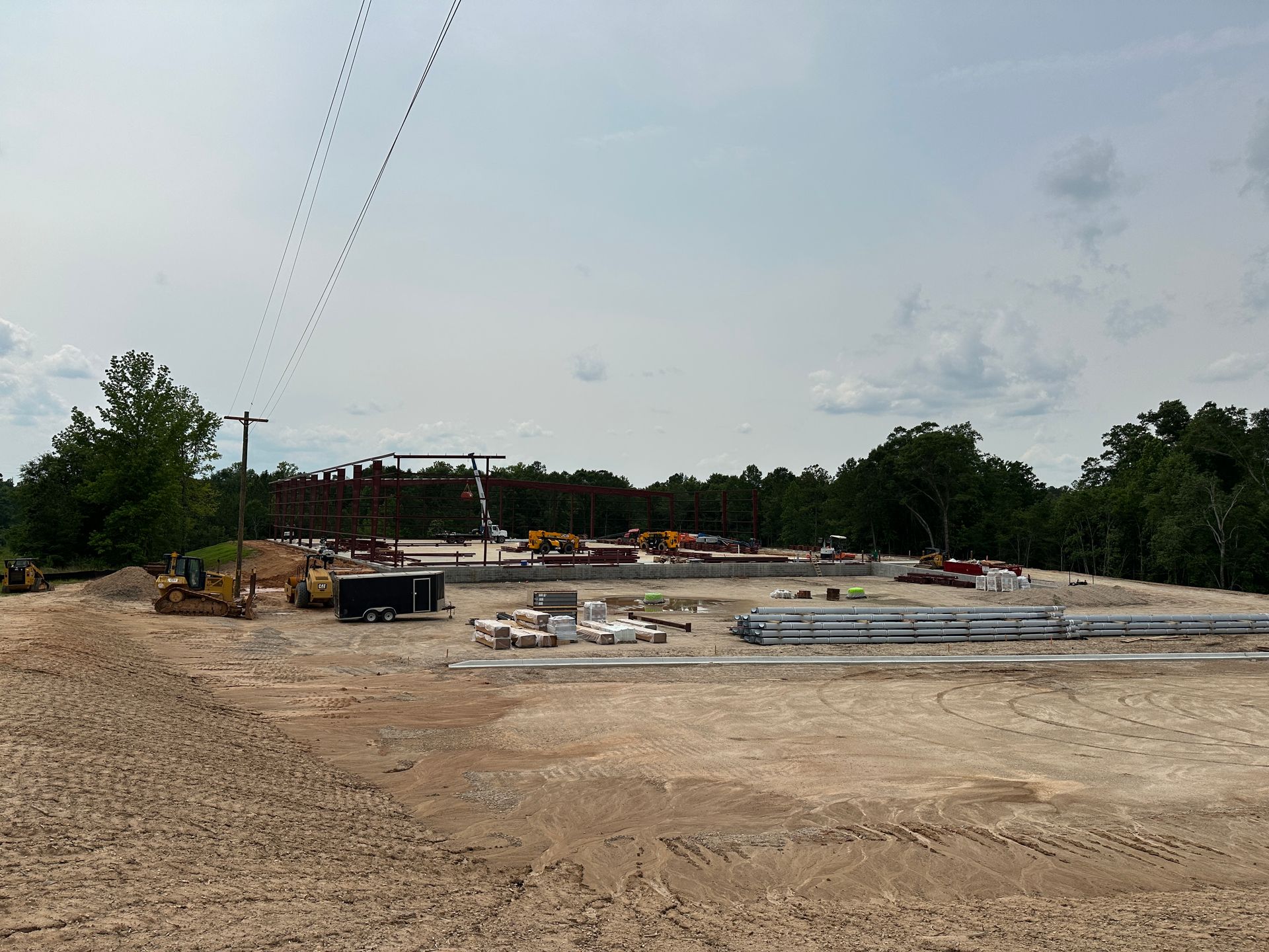 A construction site with a lot of machinery and trees in the background.