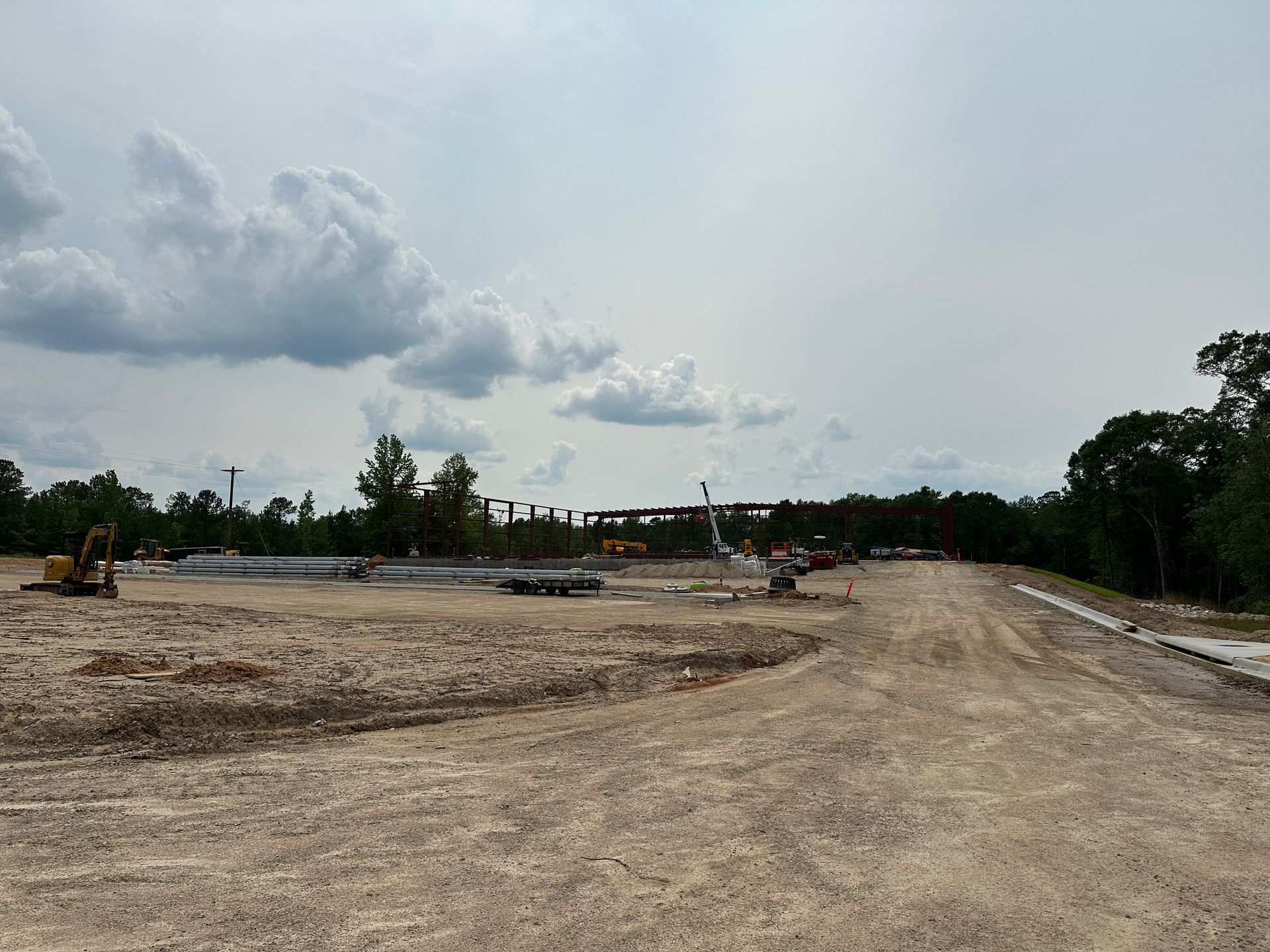 A construction site with a lot of dirt and trees in the background.