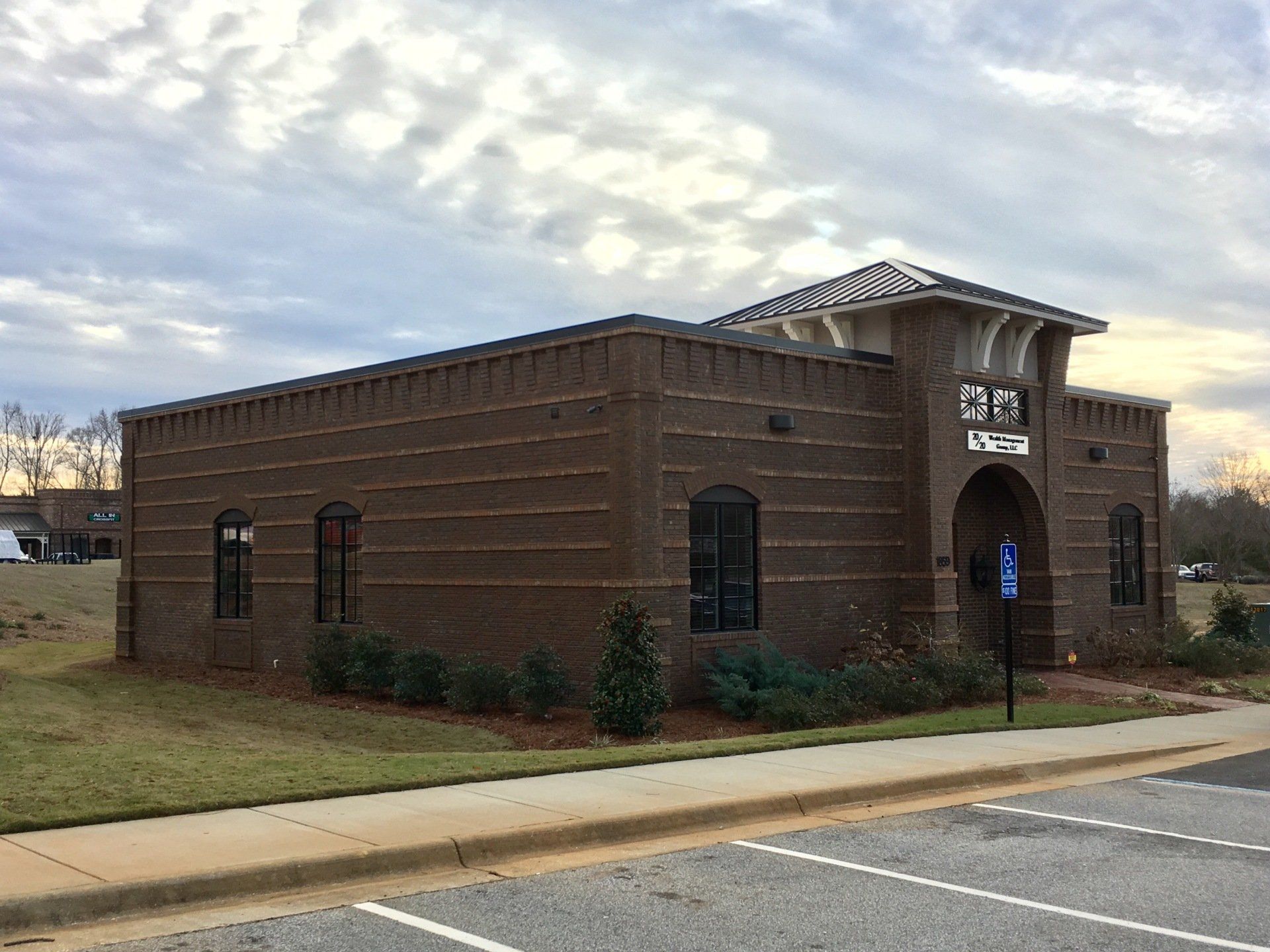 A large brick building with a lot of windows and a parking lot in front of it.