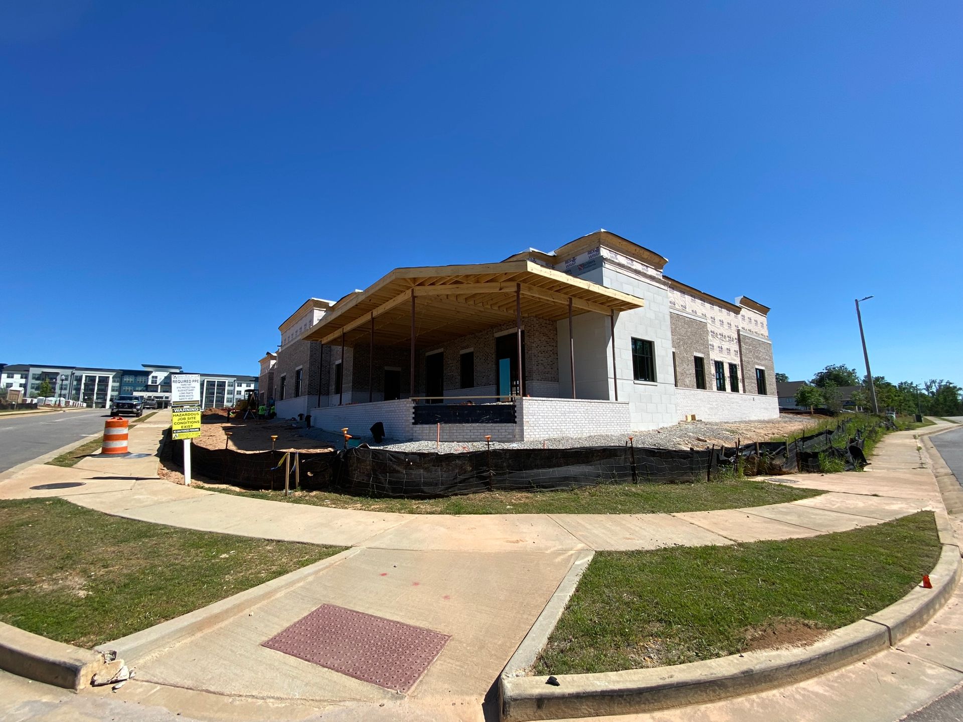 A large white building is being built on the corner of a street.