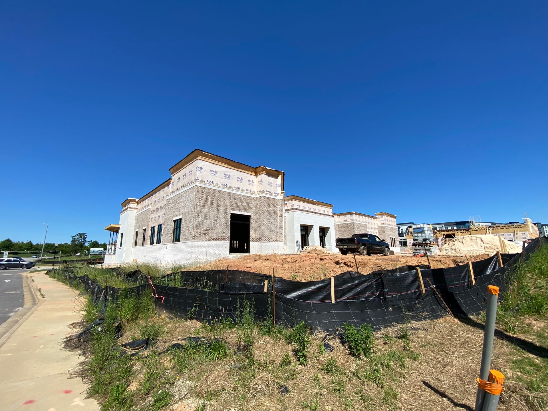 A large white building is being built in the middle of a field.