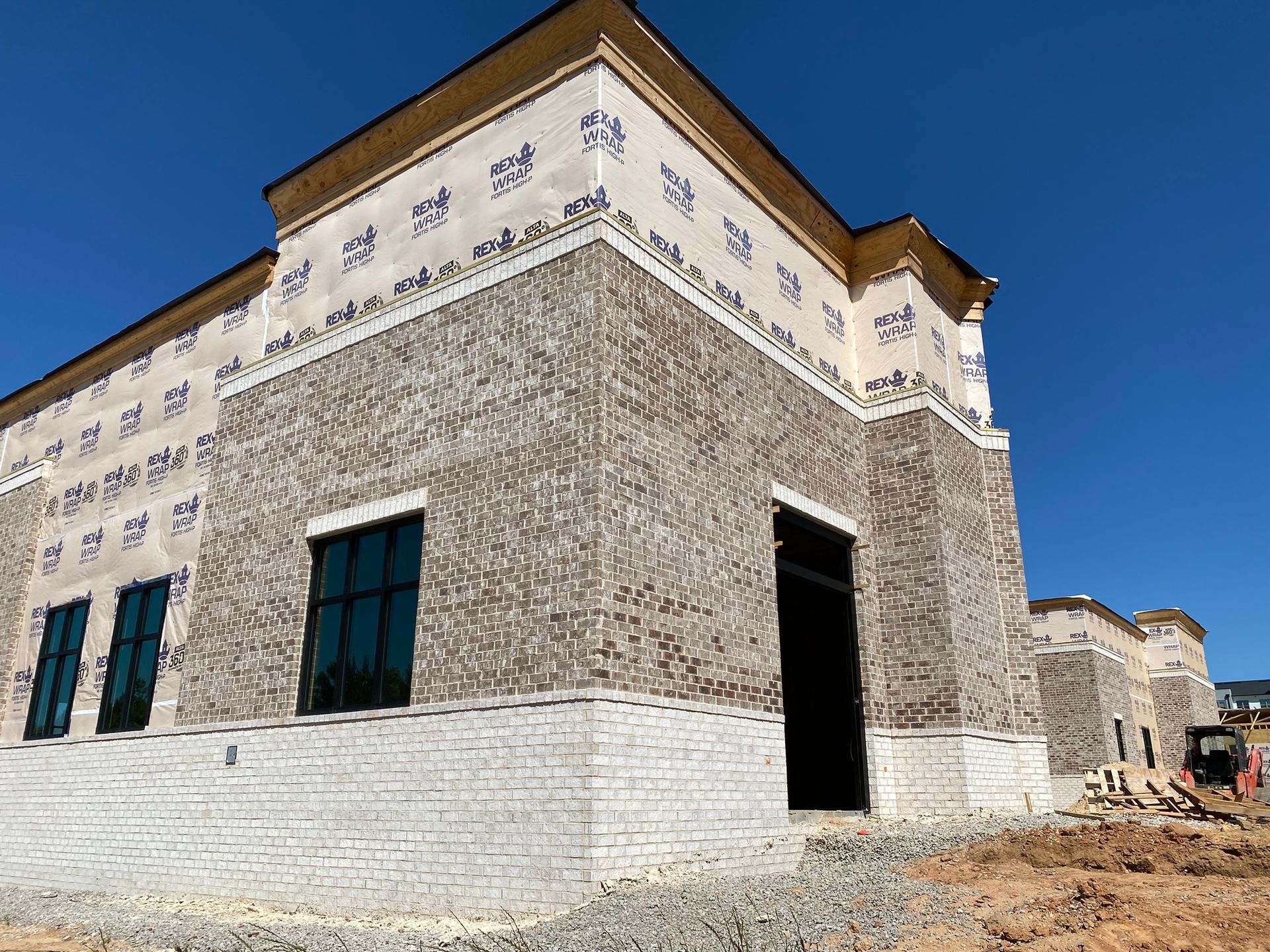 A large brick building under construction with a blue sky in the background.