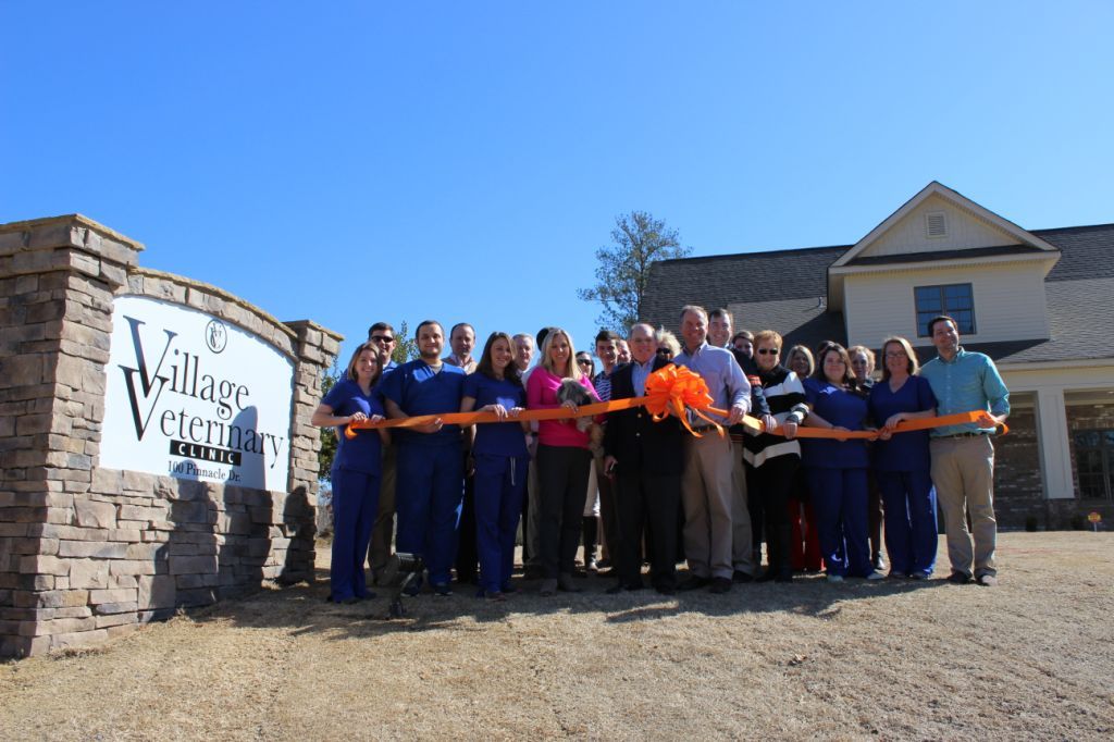 A group of people standing in front of a sign that says village veterinary