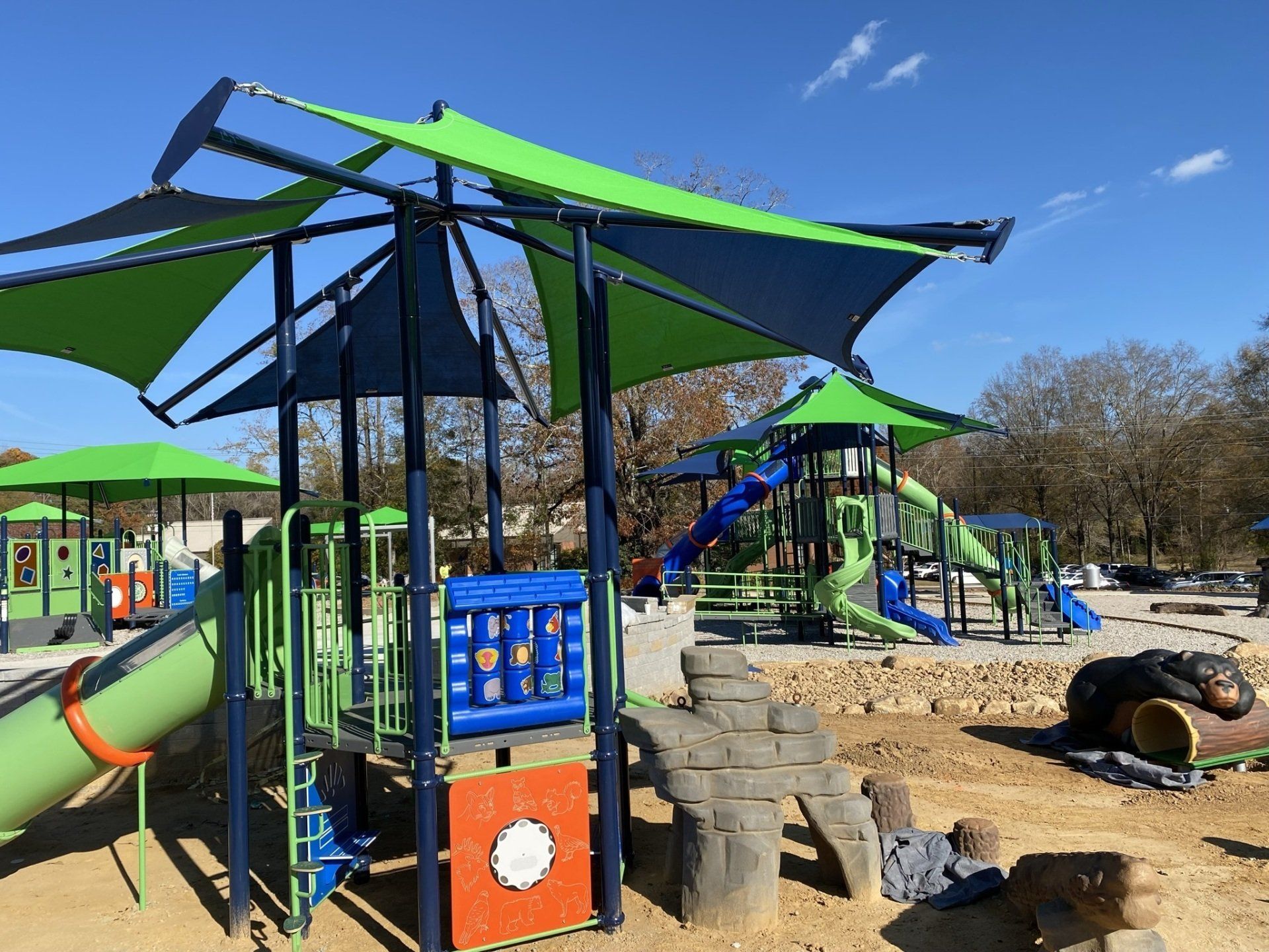 A playground with green and blue umbrellas and a slide.
