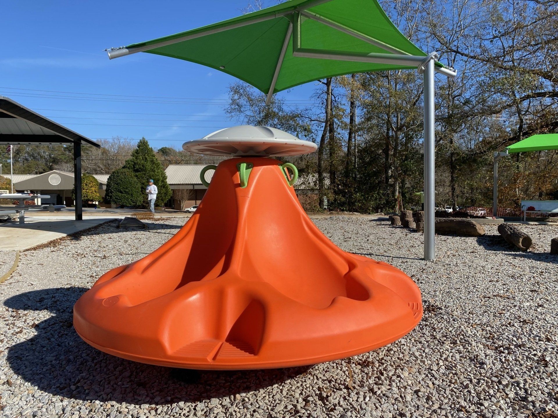An orange merry go round with a green umbrella in the background.