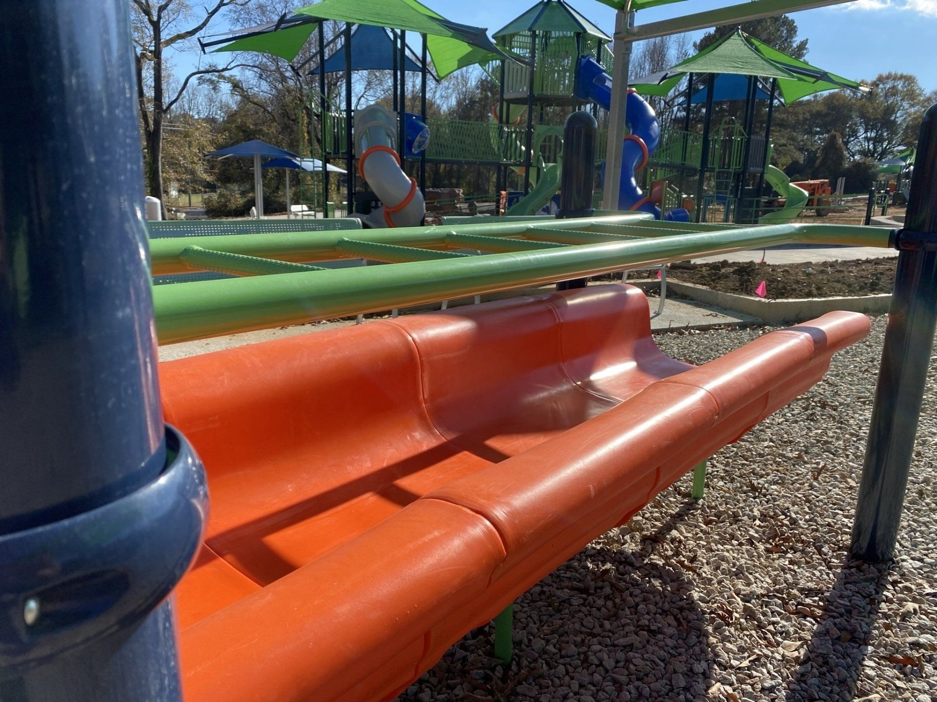 An orange slide is sitting in the middle of a playground.