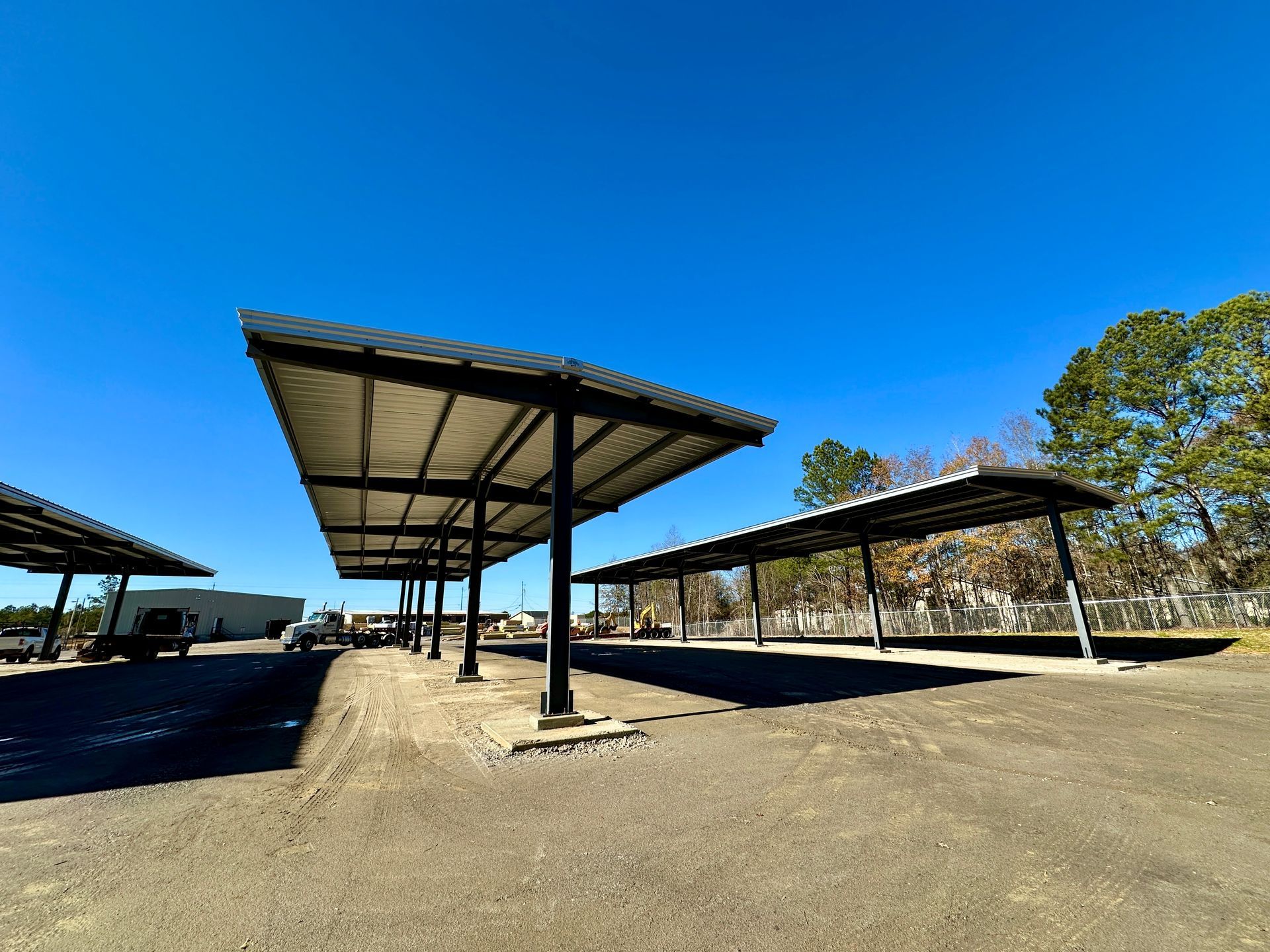 Metal carports in a gravel lot under a bright blue sky.