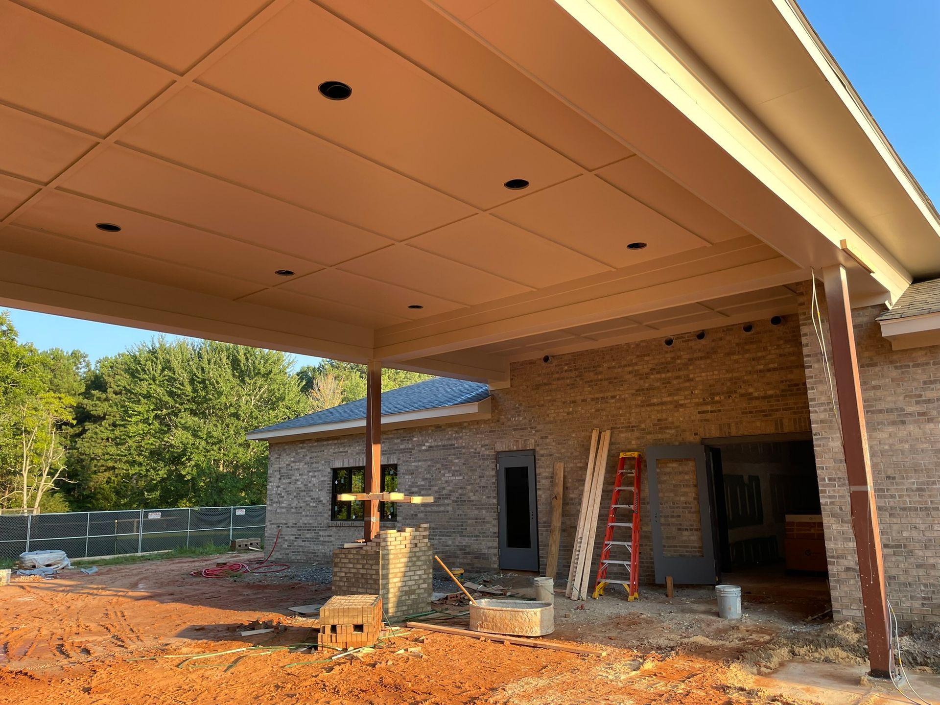 Construction site with brick walls, canopy, and exposed beams. A ladder leans against the wall.