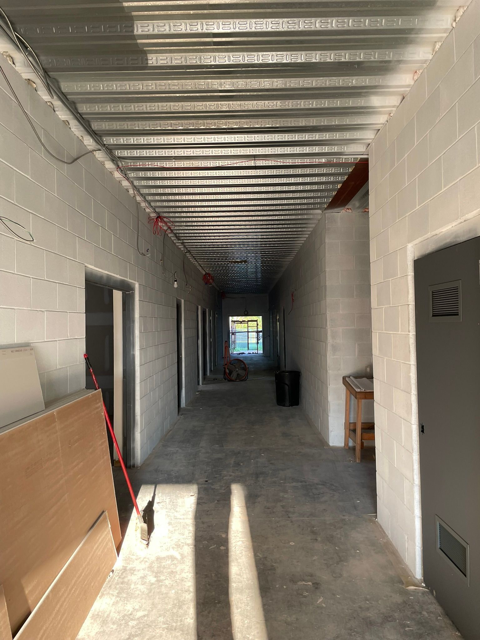 Hallway with cinder block walls, unfinished ceiling, and open doorways.