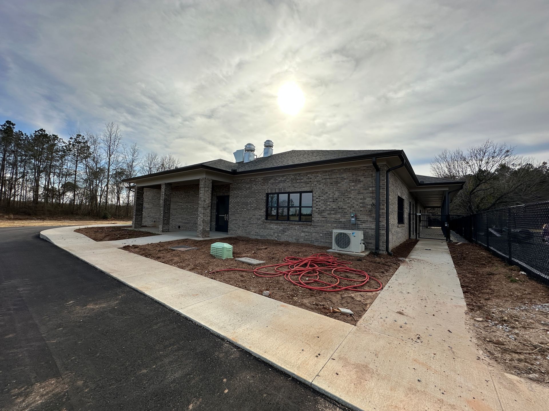 Brick building with walkway, new asphalt, and sky; possible commercial property.