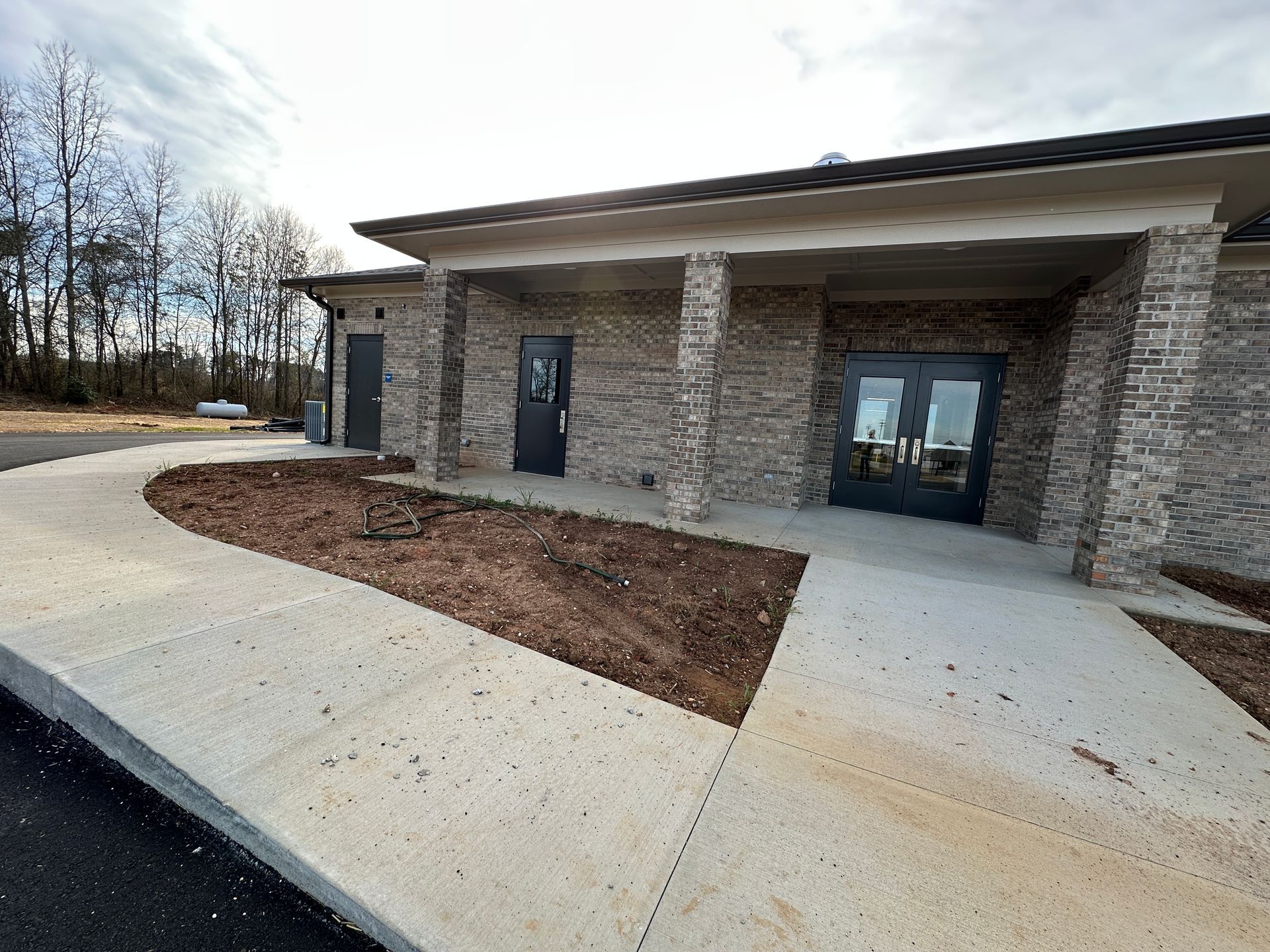 Exterior view of a brick building with a covered entrance, walkway, and landscaping.