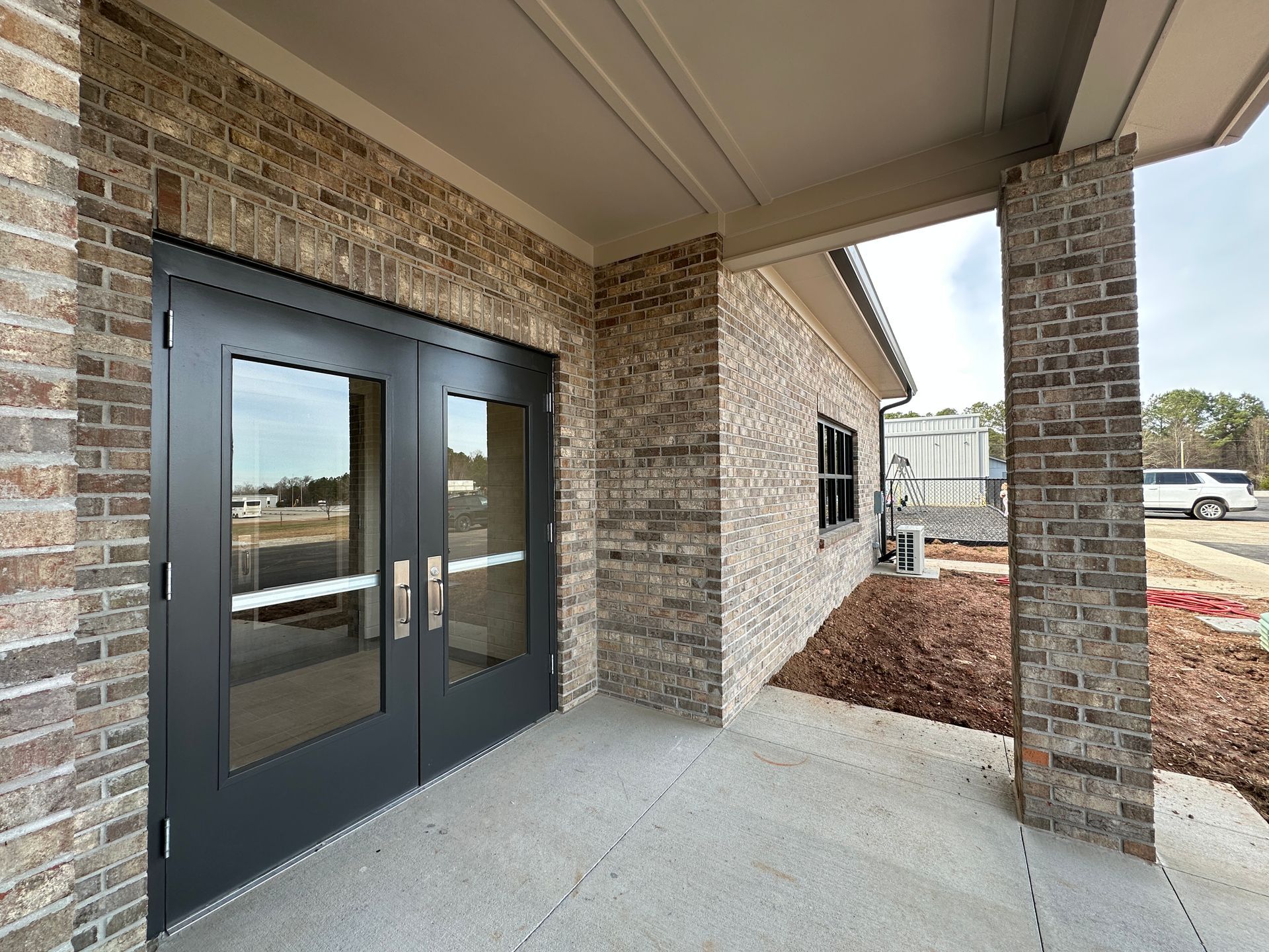 An aerial view of a new Hovey Precast office building with a blue roof surrounded by trees.