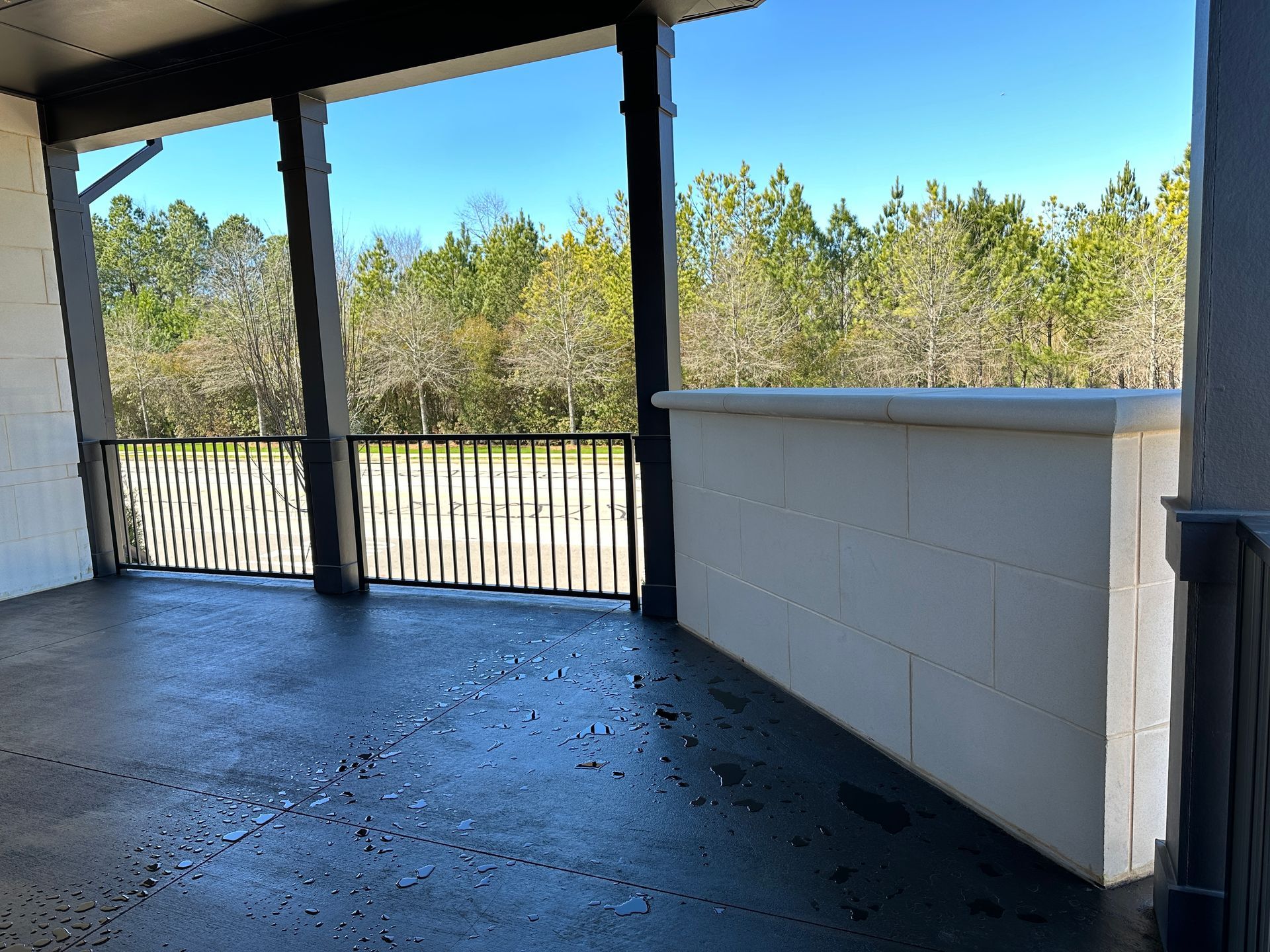 An empty porch with a railing and trees in the background