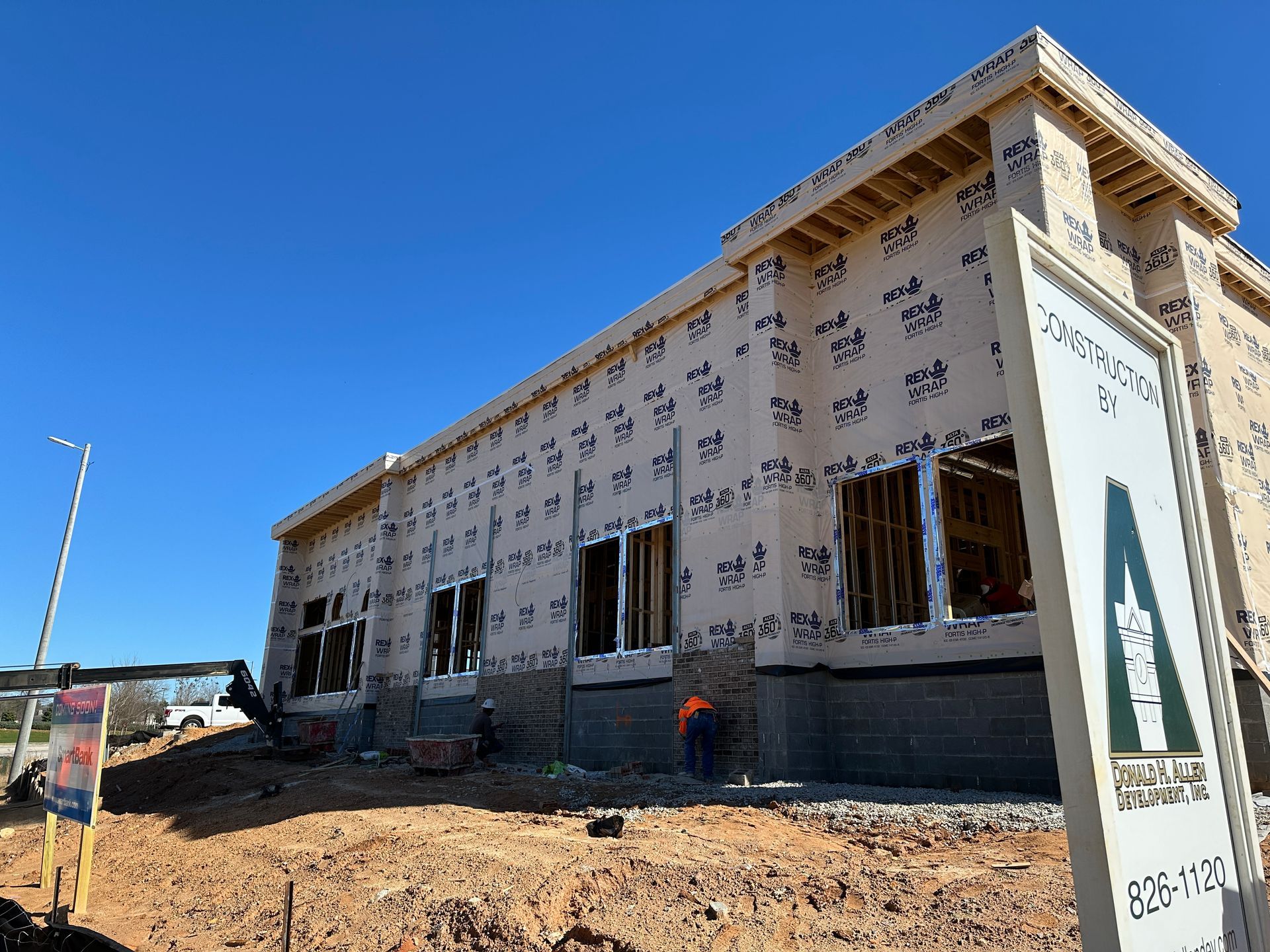 A large building is being built on a dirt hill.