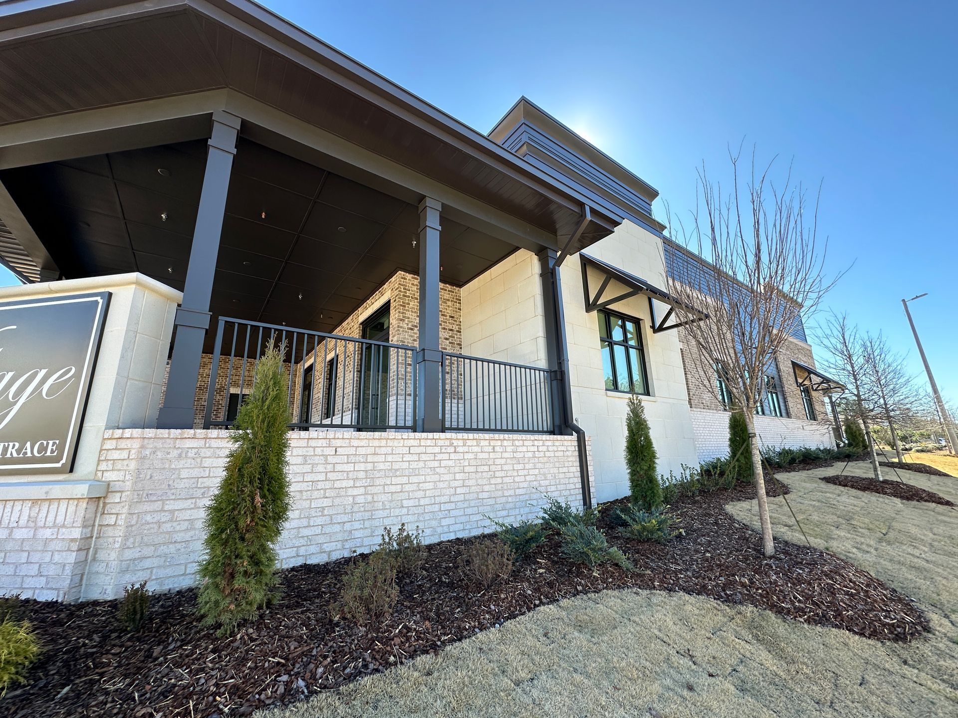 A large building with a porch and a sign in front of it.