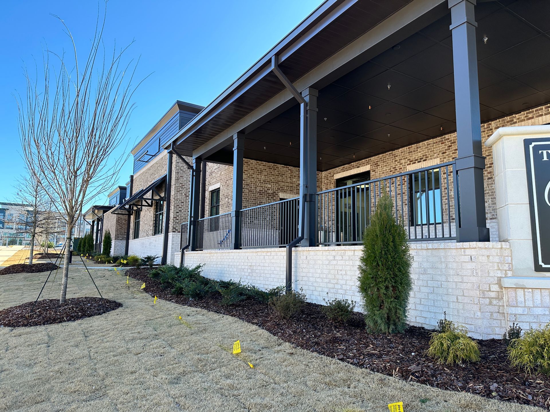 A large building with a porch and a sign in front of it.