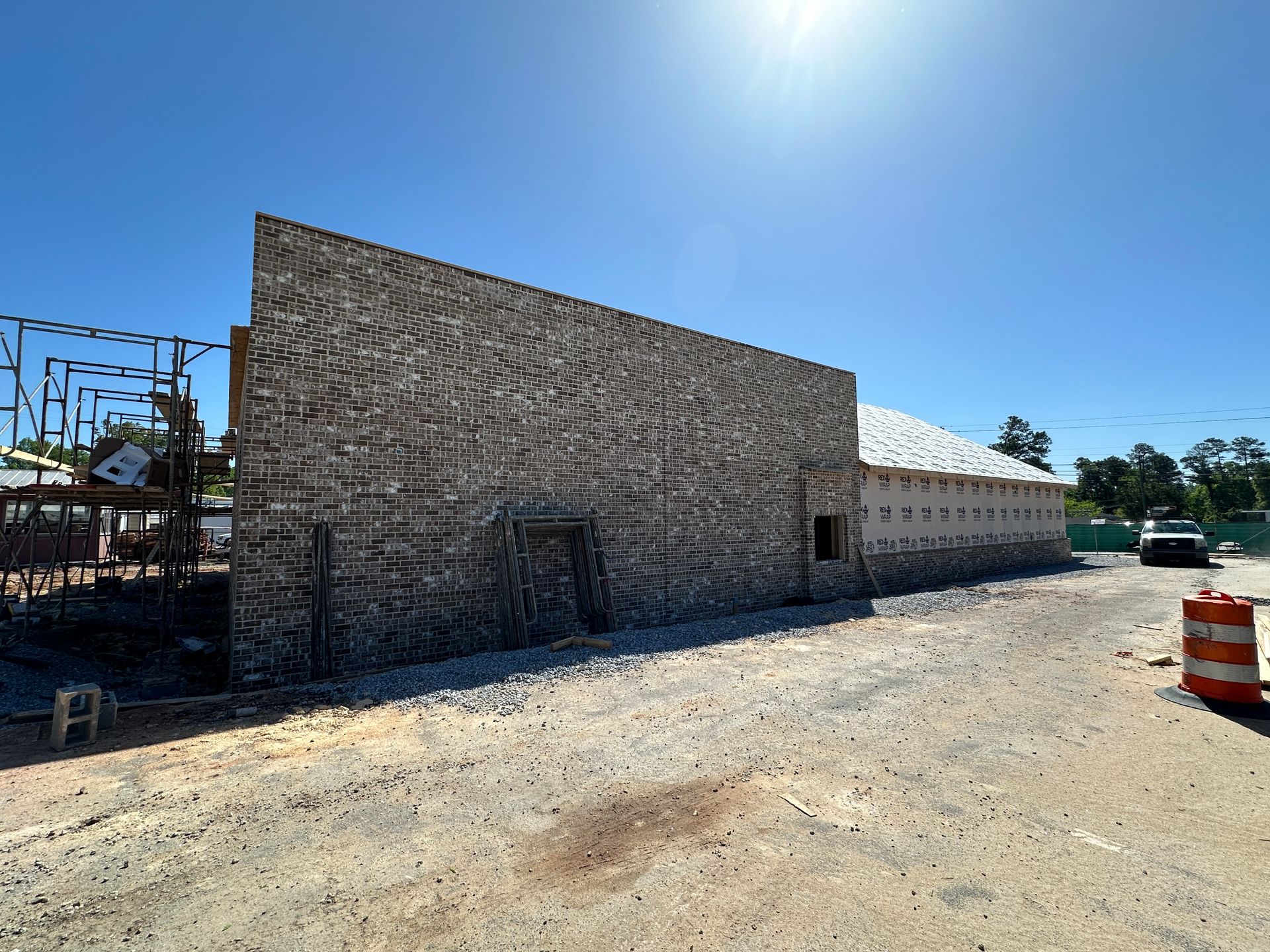 A large building is being built on a dirt road.