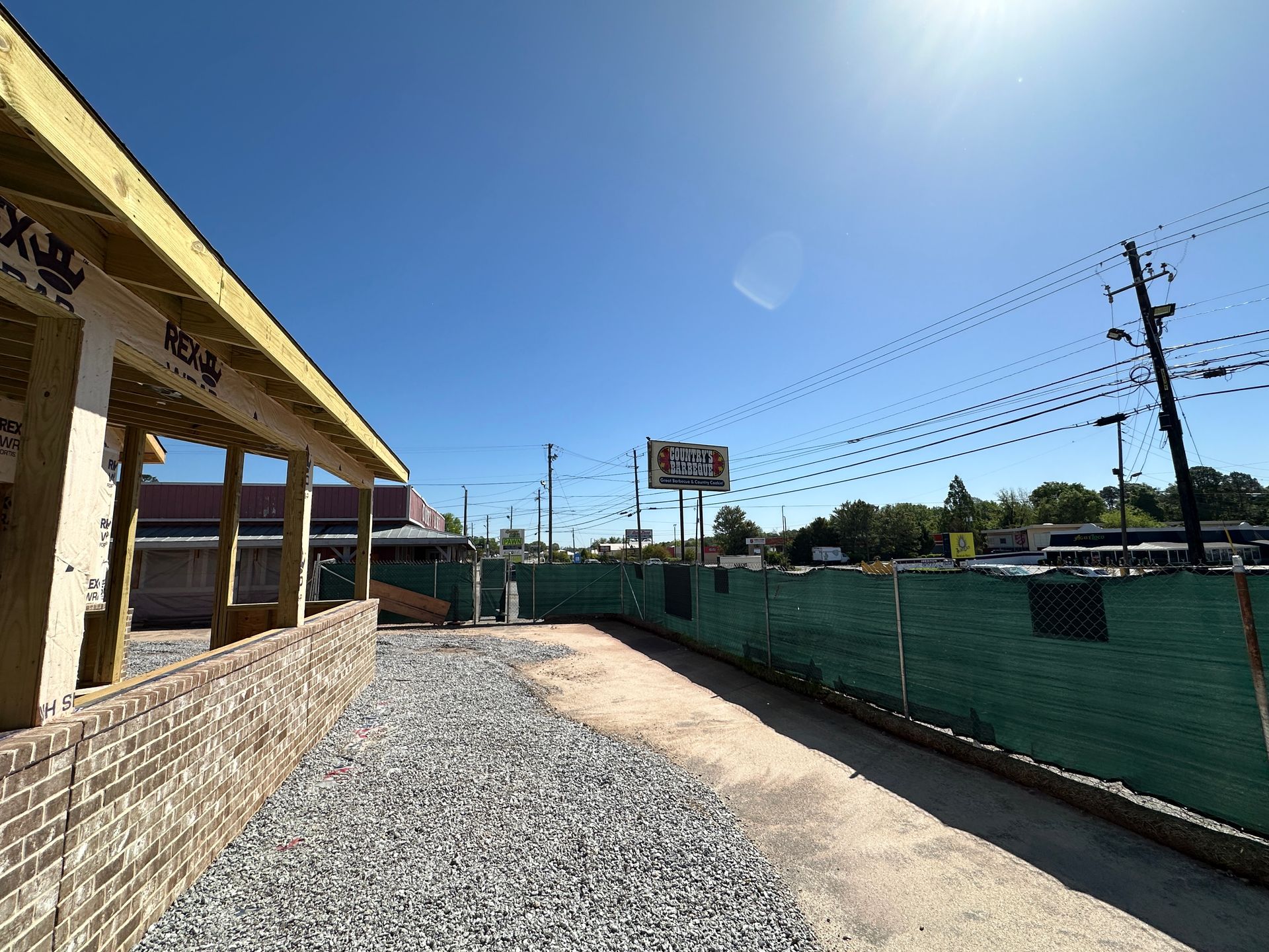 A brick building is being built next to a green fence.