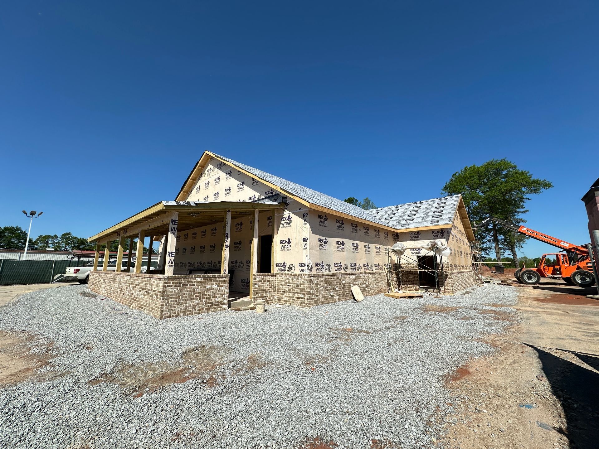 A house is being built on a gravel lot.