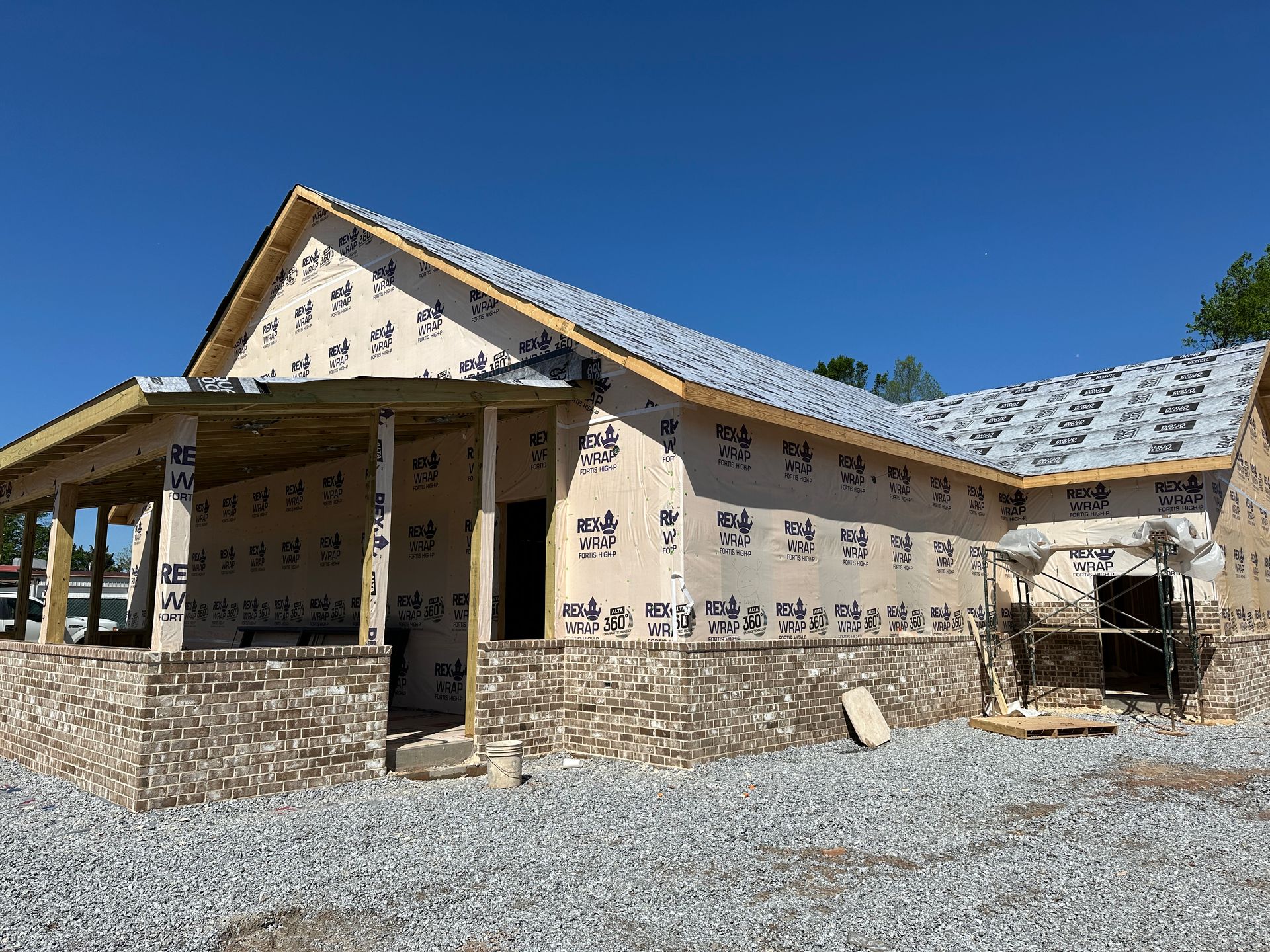 A house is being built with a stone wall and a porch.