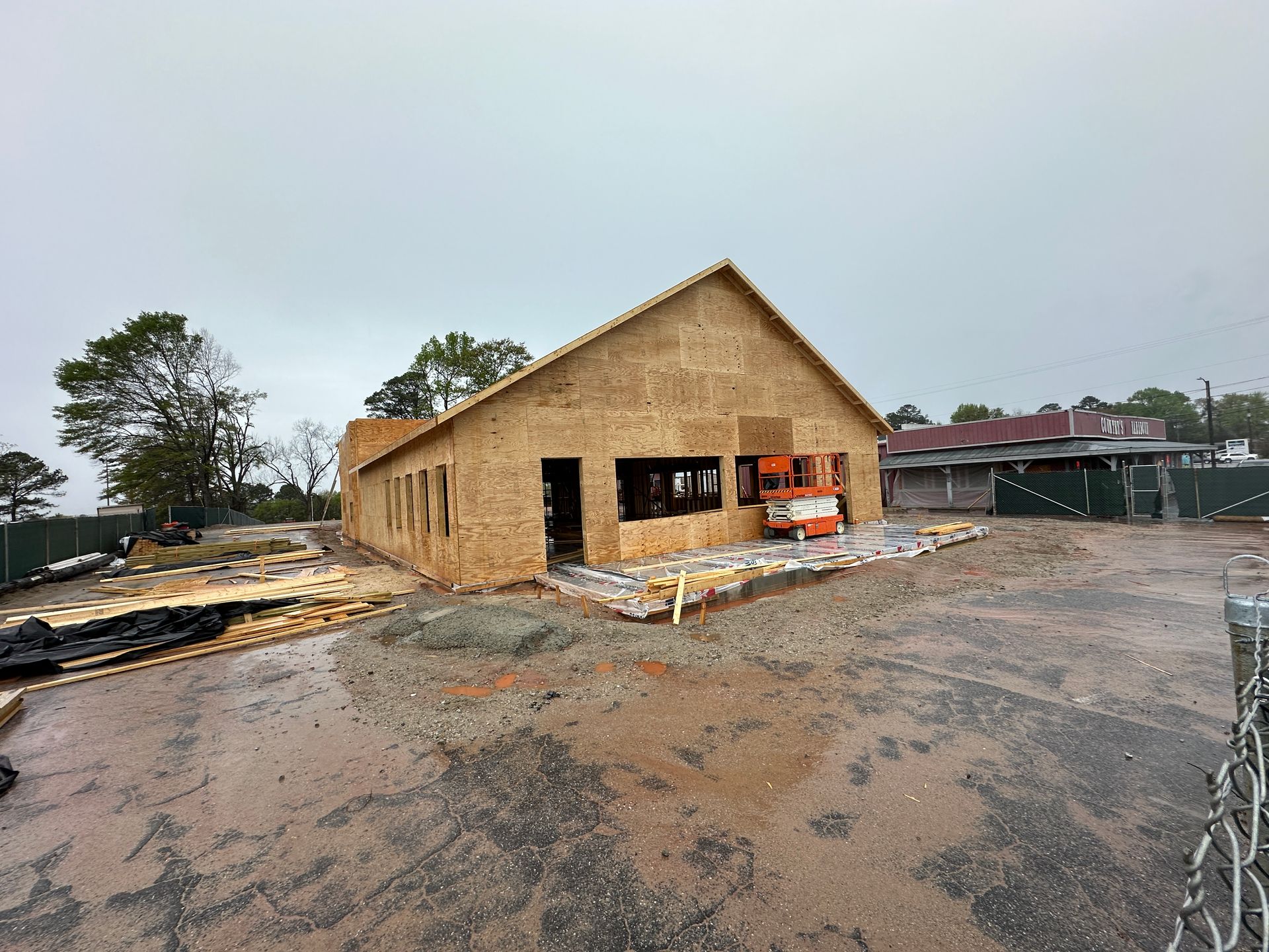 A large wooden building is being built in a dirt lot.