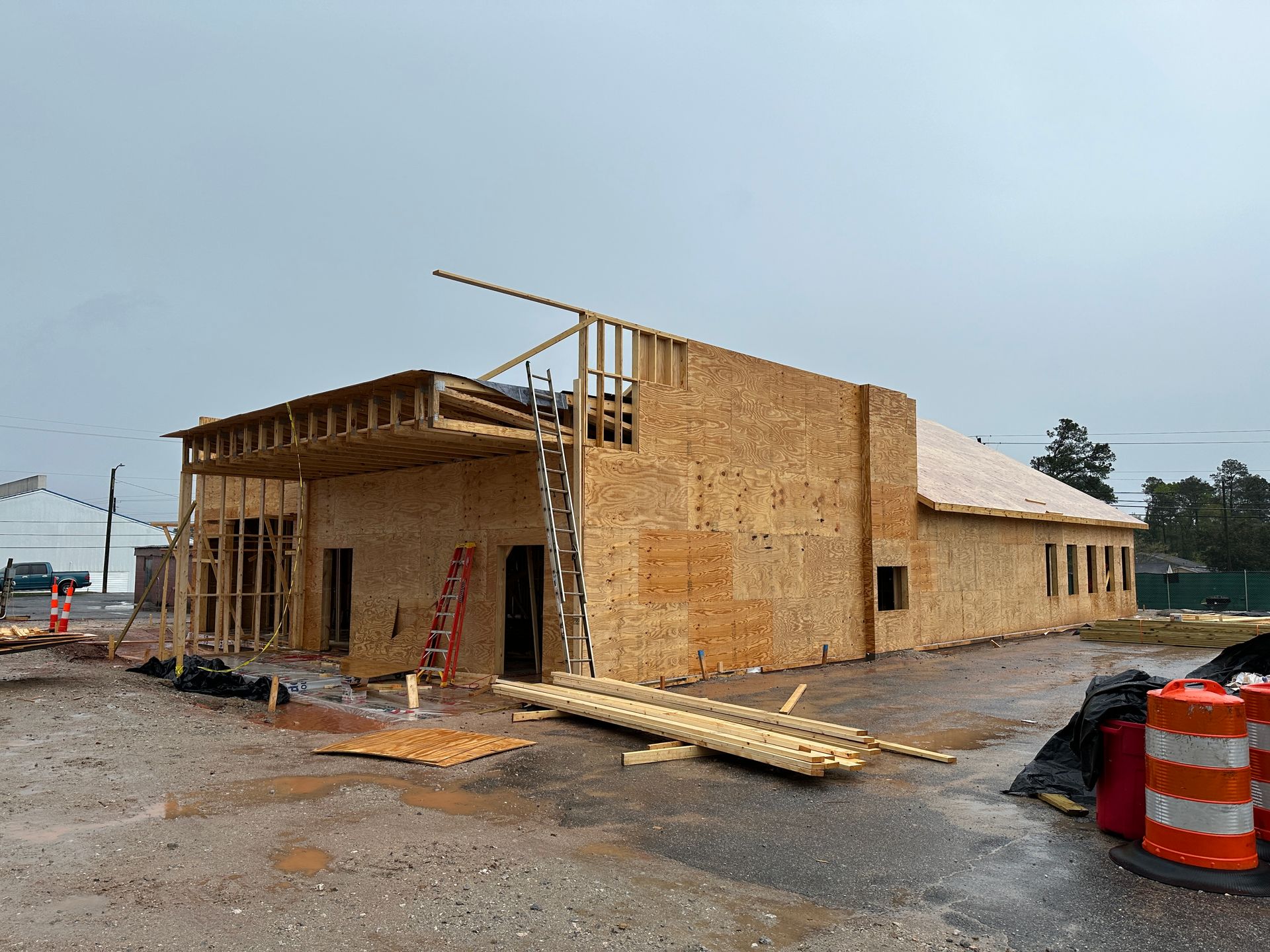 A large wooden building is being built on a dirt road.