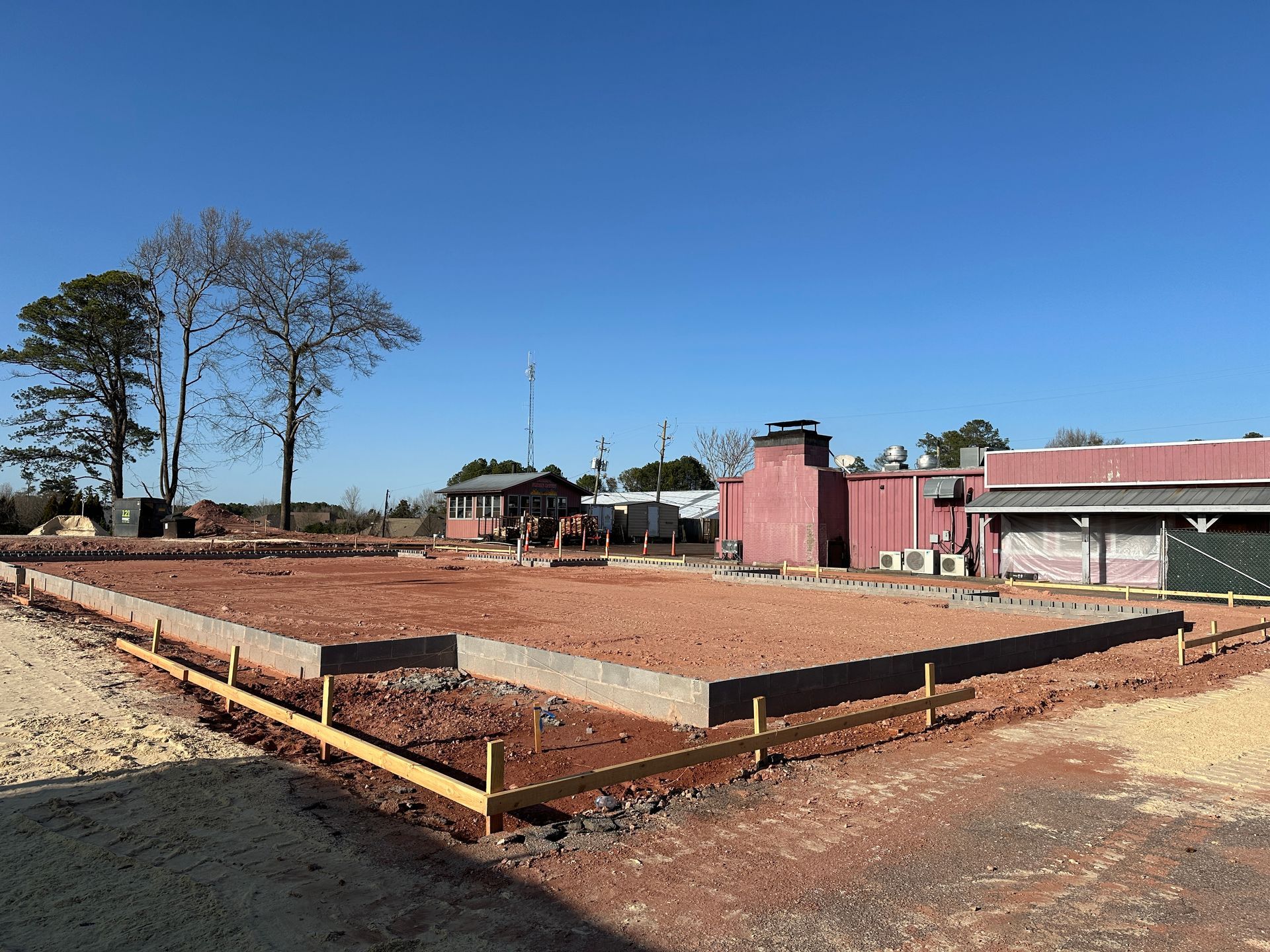 A large building is being built in the middle of a dirt field.