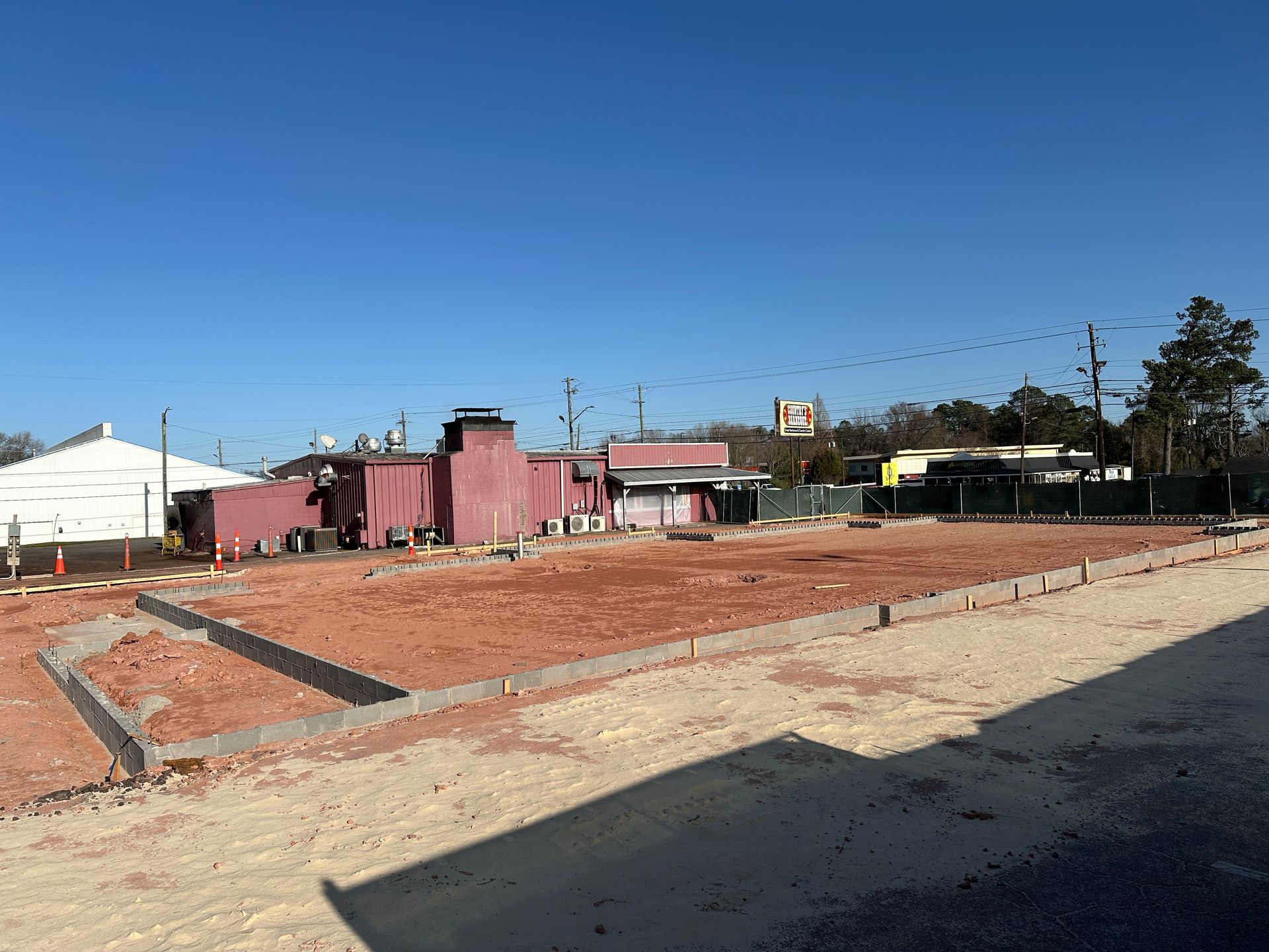 A large pink building is sitting in the middle of a dirt field.