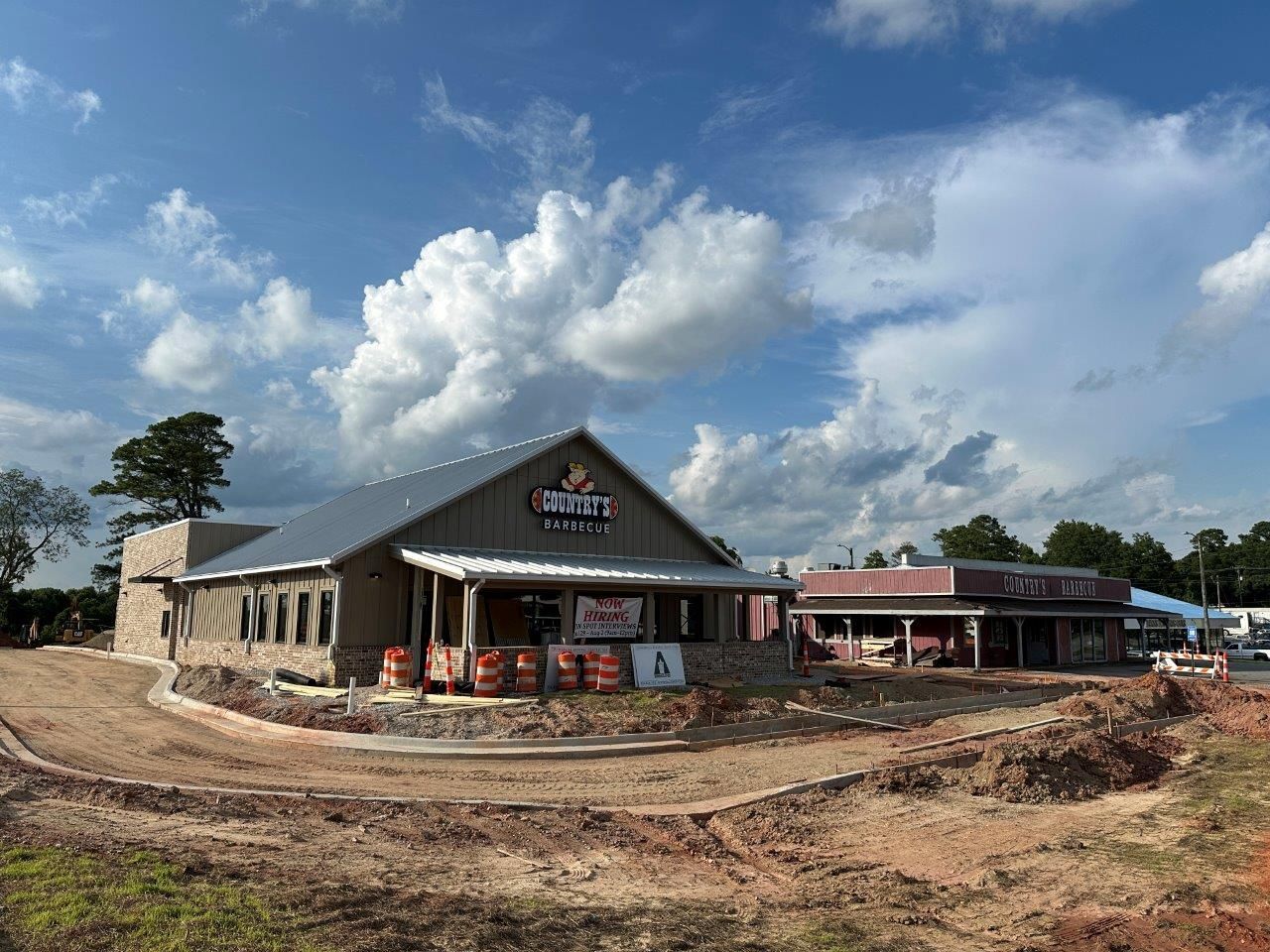 A large building is being built in the middle of a dirt field.