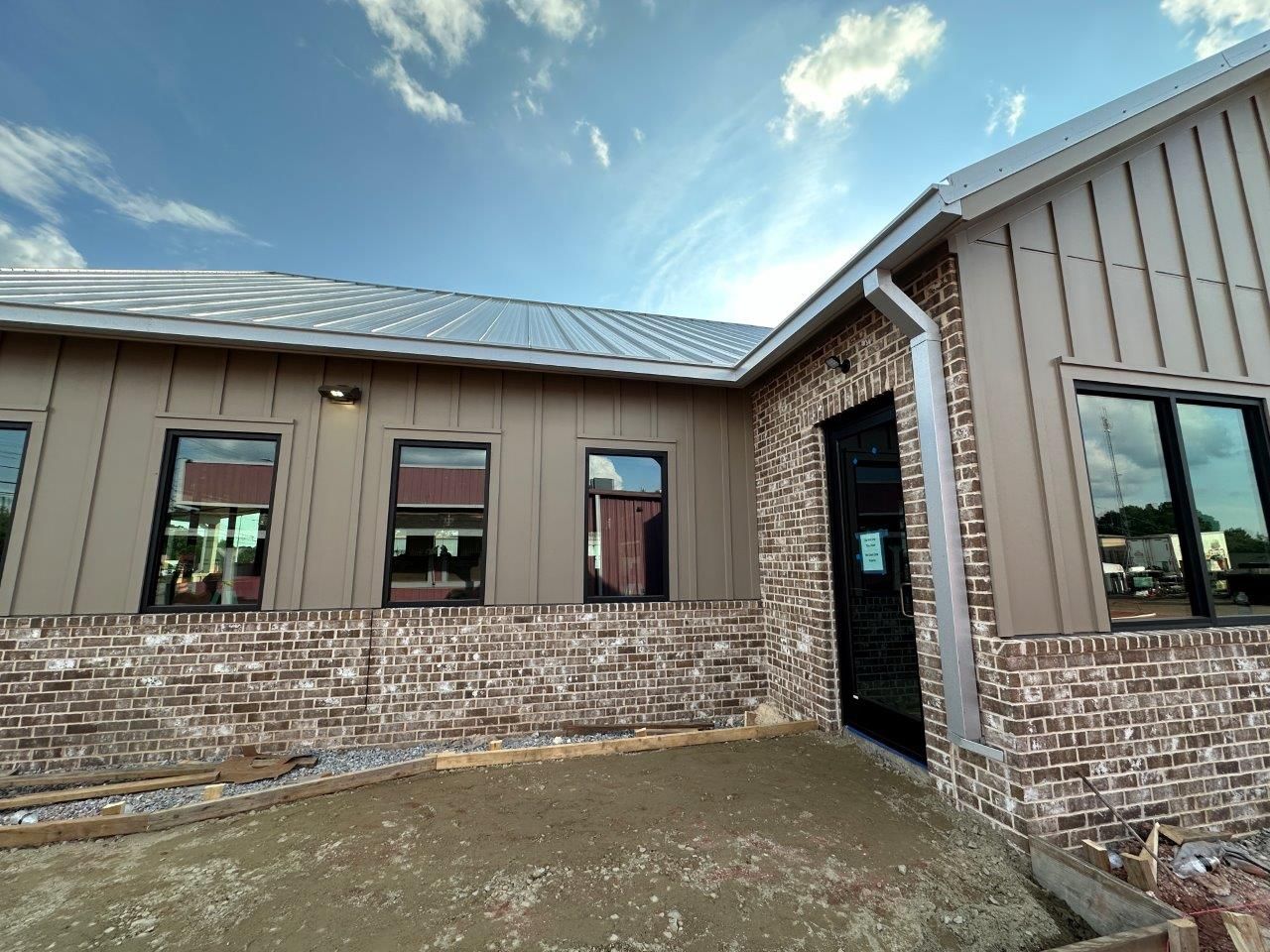 A brick building with a metal roof and a lot of windows