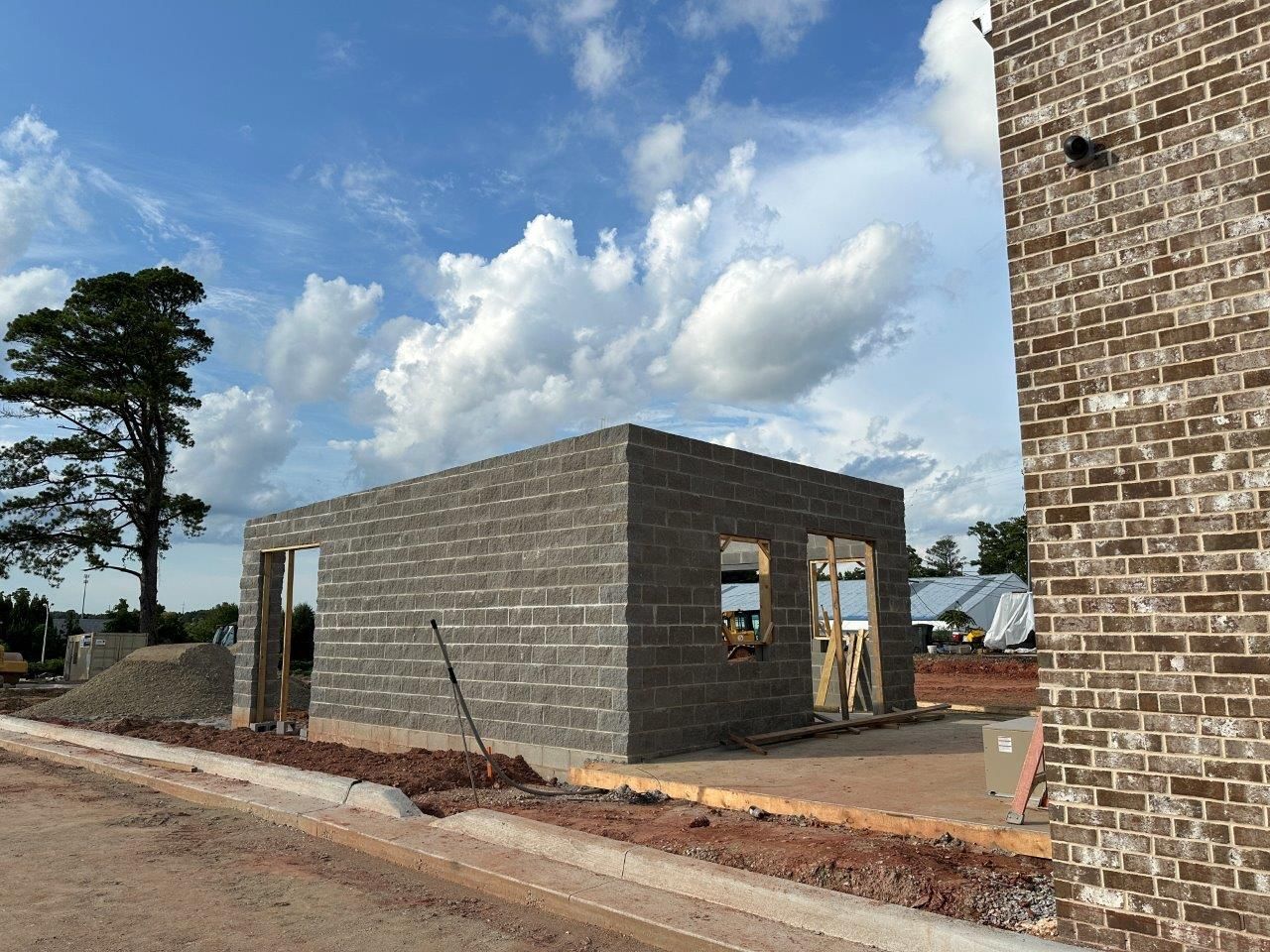 A brick building is being built on the side of a road.