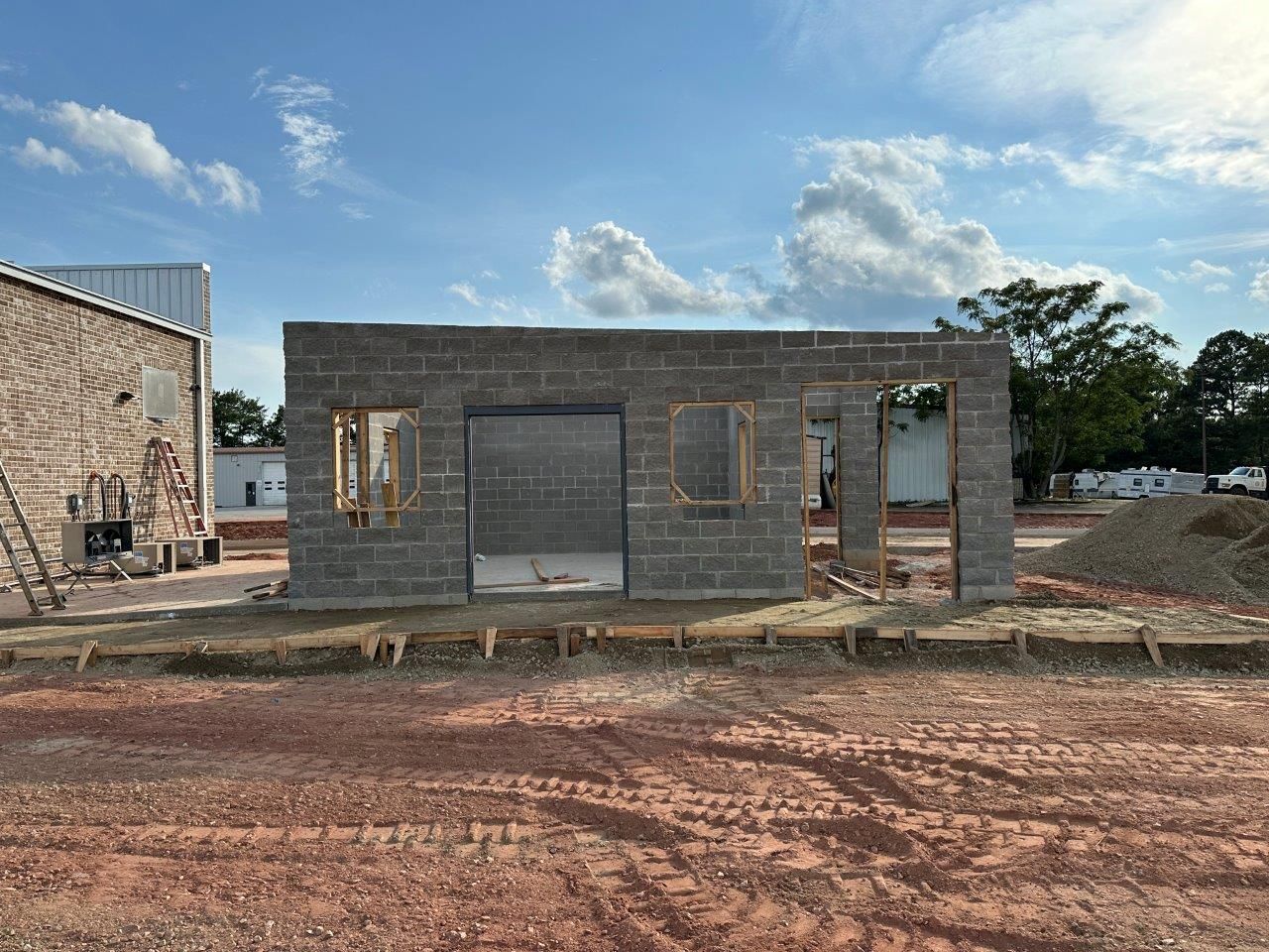 A brick building is being built in a dirt field.